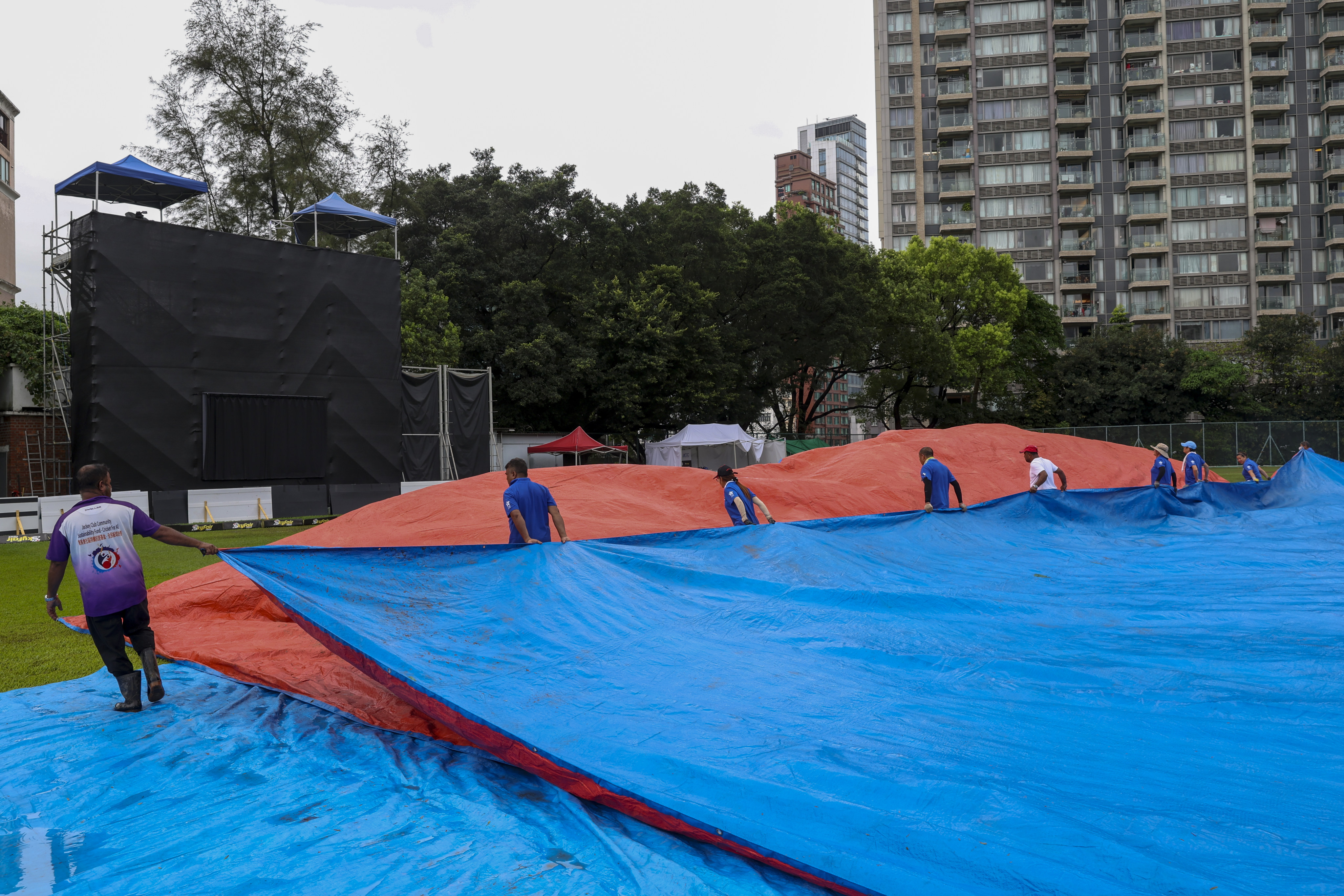 The covers are brought on to protect the pitch from the downpour as matches are disrupted at Tin Kwong Road Recreation Ground. Photo: Yik Yeung-man