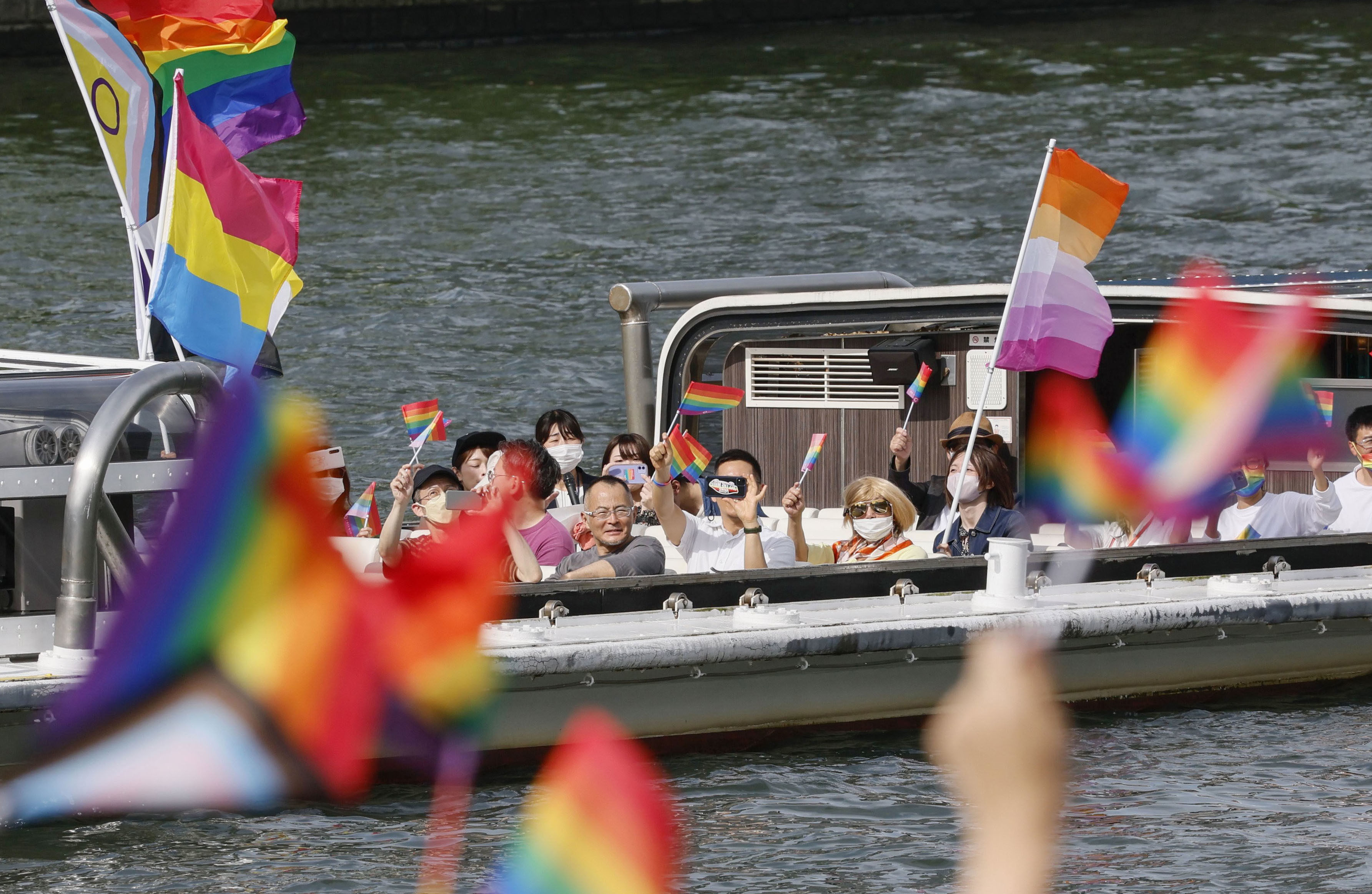 People wave rainbow flags aboard a boat during Pride Cruise Osaka on May 28. Photo: Kyodo