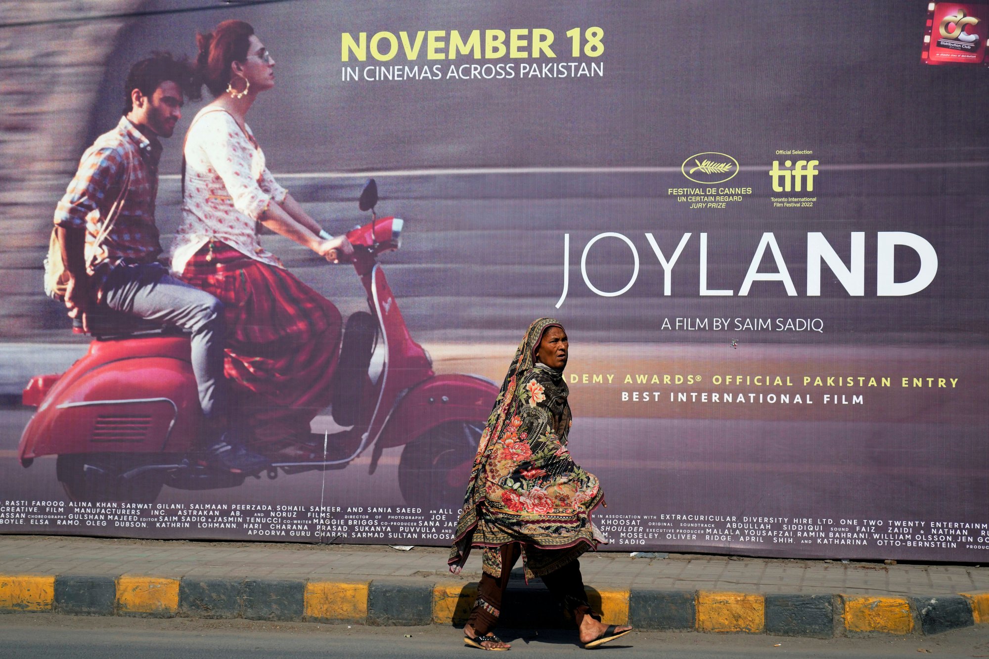 A woman walks past an advert for the Pakistani film ‘Joyland’ outside a Lahore cinema in November. The Oscar contender caused uproar for its depiction of a relationship between a married man and a trans woman. Photo: AP