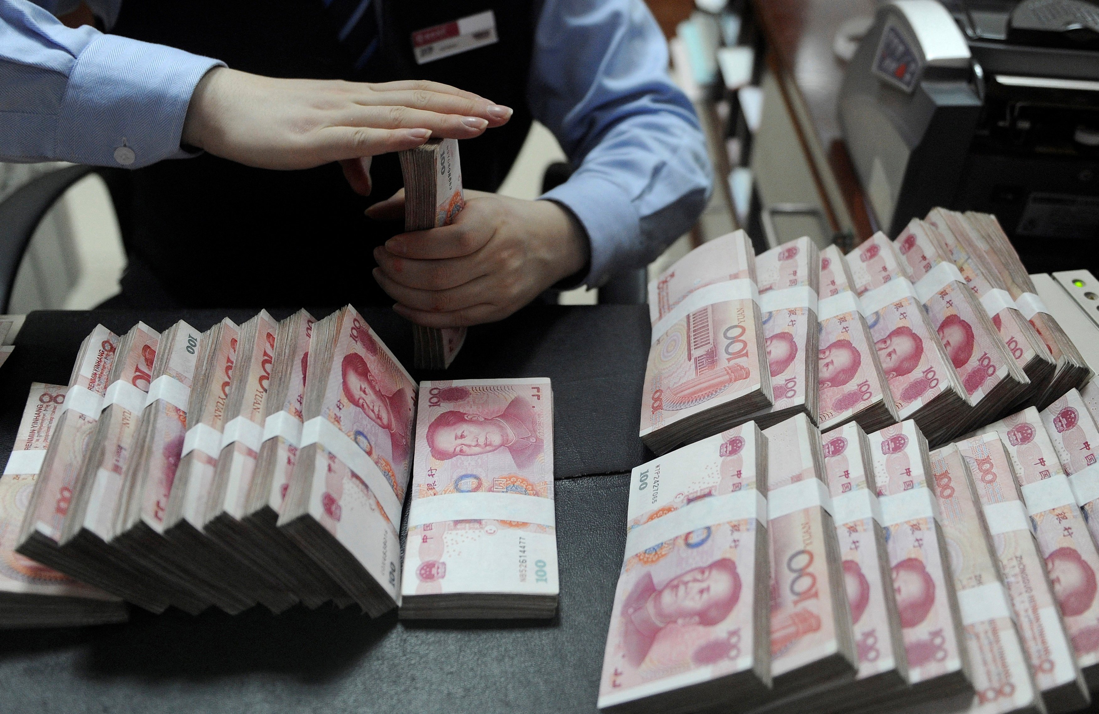 An employee counts 100 yuan notes at a bank in Hefei, Anhui province. The growing spread between US and Chinese government bond yields is one of several factors driving the prospect of a weaker yuan. Photo: Reuters