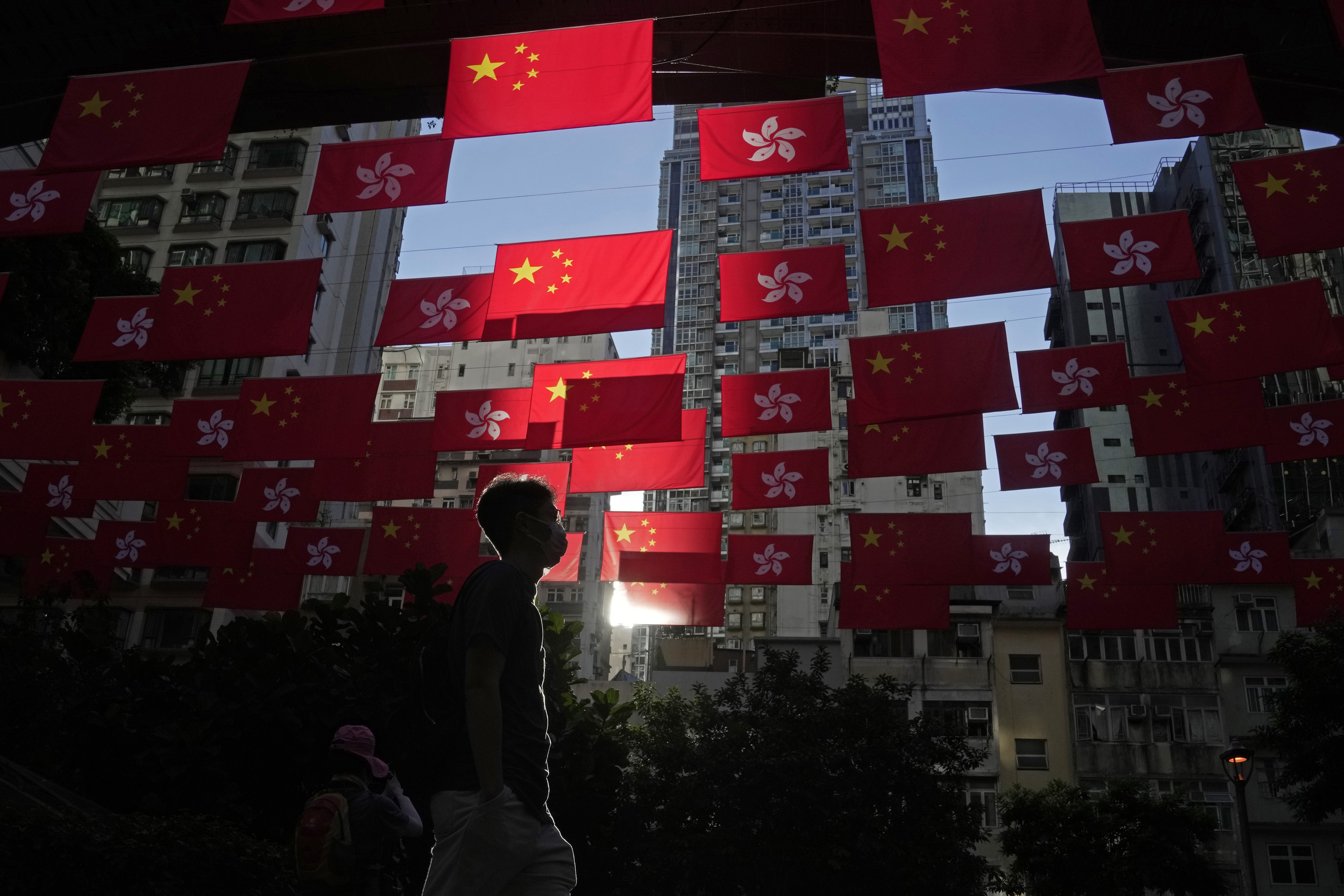 A man passes by Chinese and Hong Kong flags during last year’s 25th anniversary of the city’s handover to China. This year’s anniversary celebration will be the first since the city’s emergence from the pandemic. Photo: AP