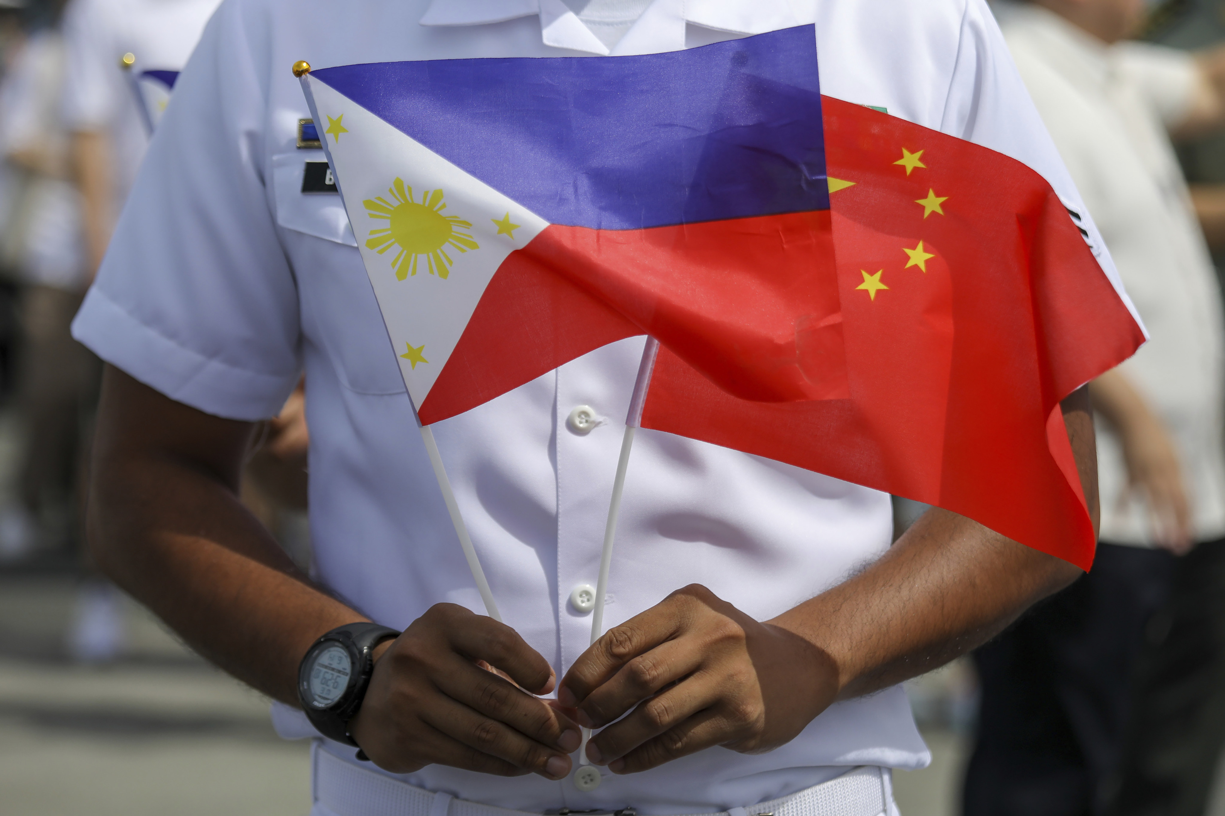 A member of the Philippine coastguard holds the national flags of the Philippines and China to mark the arrival of a Chinese naval training ship on a goodwill visit earlier this month. Photo: AP