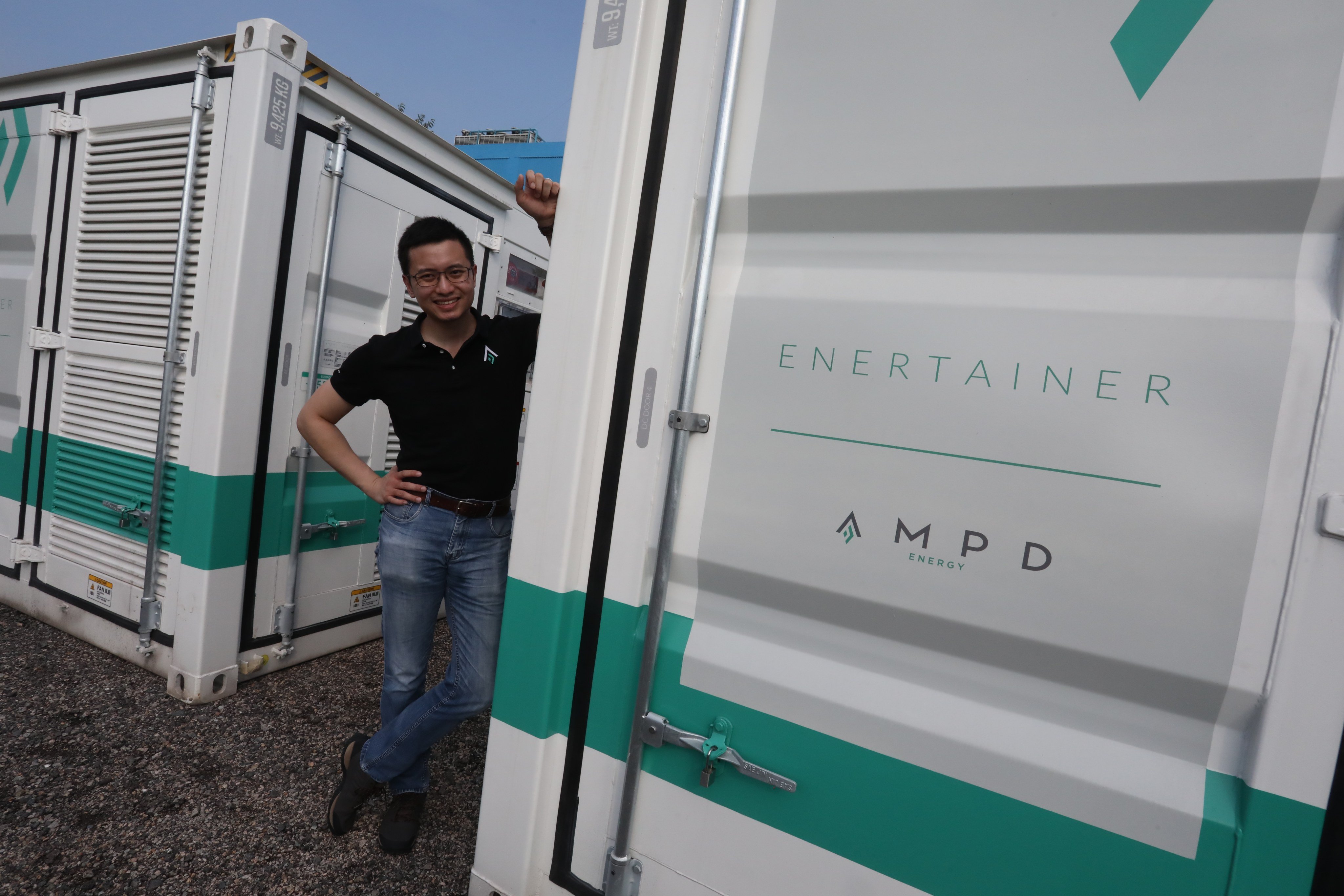 AMPD Energy’s CEO Brandon Ng with an AMPD Enertainer, a containerized energy storage system, at Tseung Kwan O Industrial Estate. Photo: SCMP/ Jonathan Wong