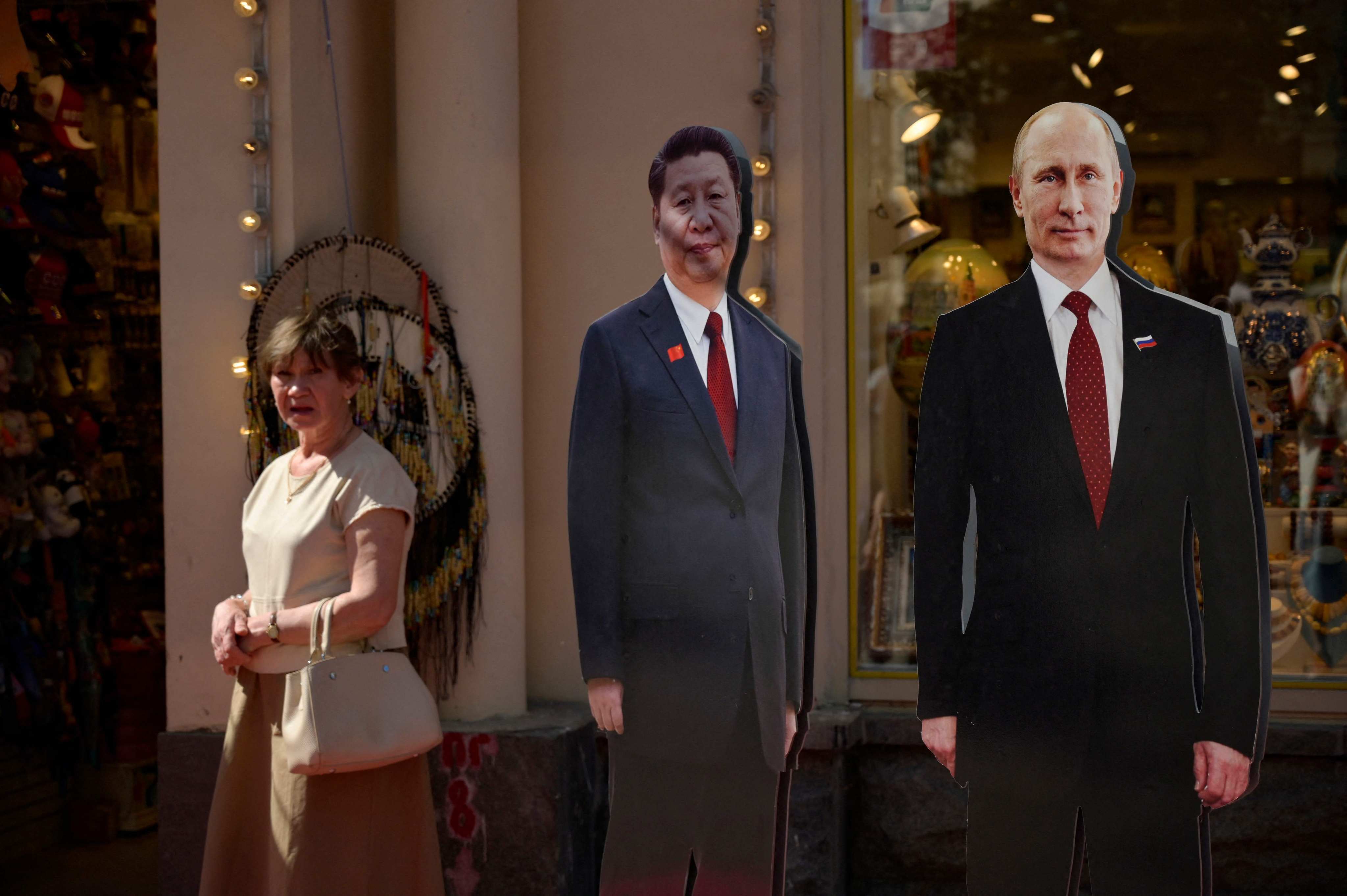A woman stands next to cardboard cutouts of Russian President Vladimir Putin and Chinese President Xi Jinping in Moscow on June 14. Photo: AFP