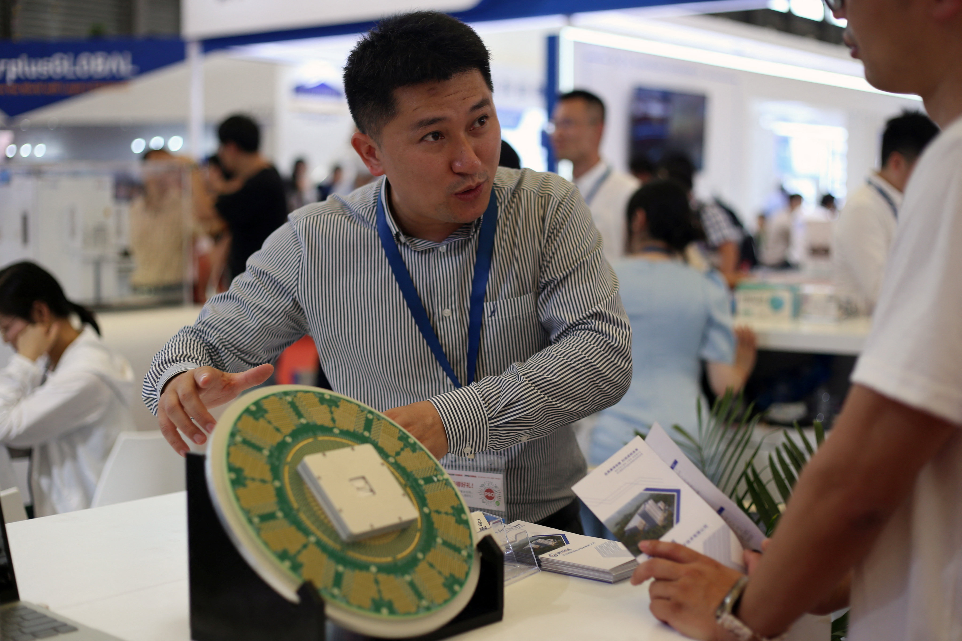 A staff member for Shanghai Precision Measurement Semiconductor Technology gestures next to a giant mock-up chip during Semicon China, a trade fair for the semiconductor industry, in Shanghai on June 29, 2023. Photo: Reuters