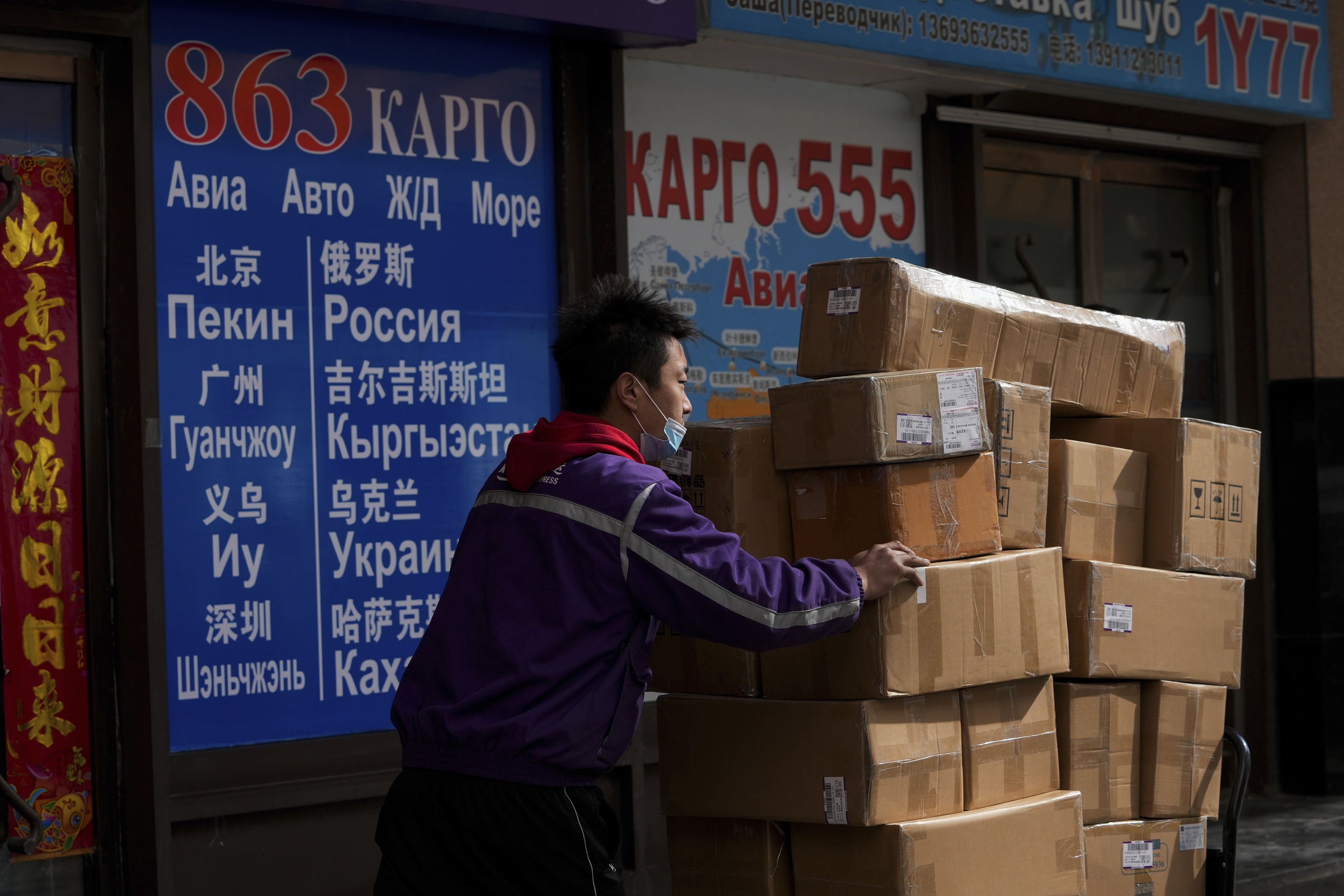 A courier worker moves goods past a shipping company for countries including Russia and Ukraine, at a trading centre also known as the Russia Market in Beijing. Photo: AP