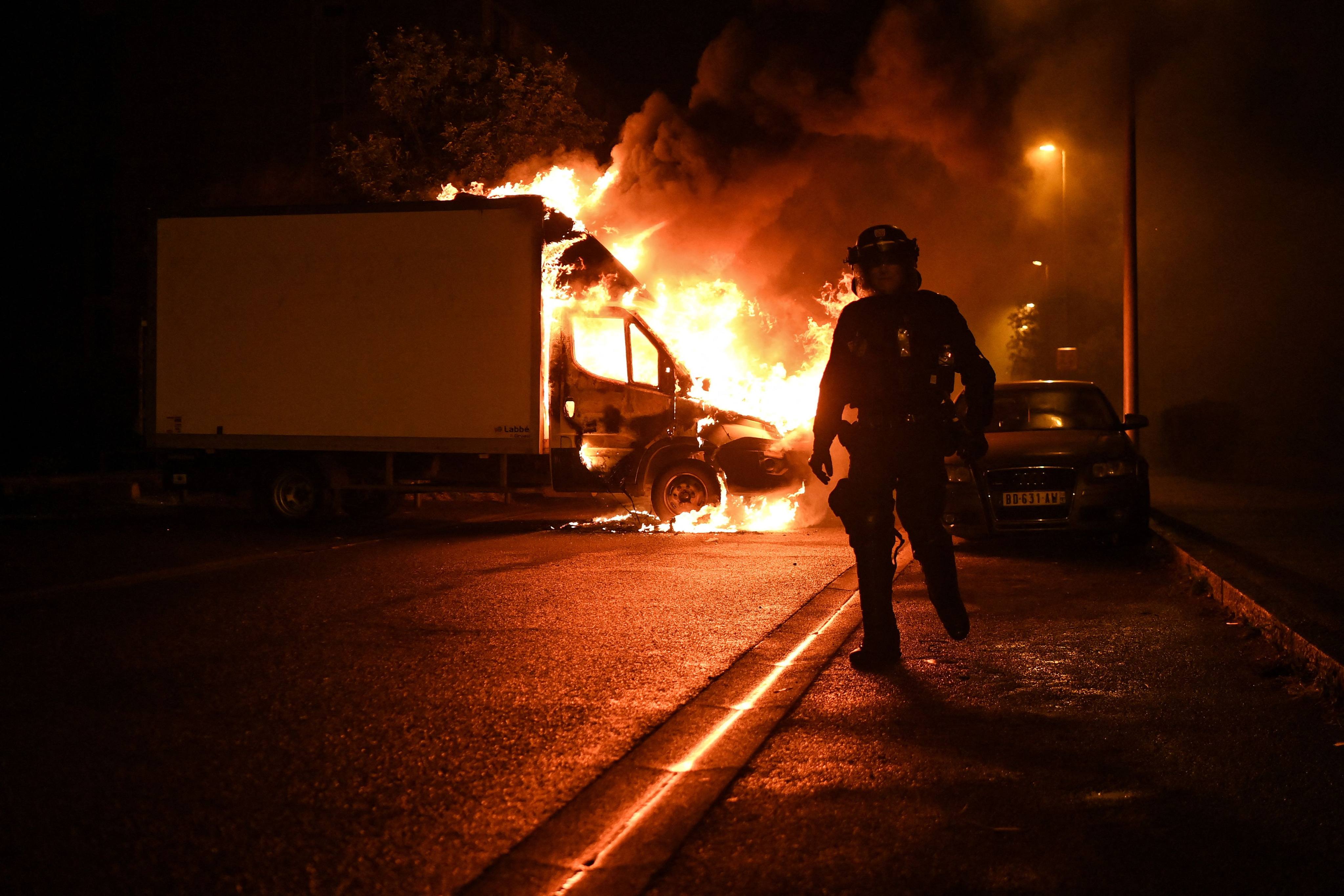An anti-riot police officer walks past a burning truck in Nantes, western France, on July 1. Photo: AFP