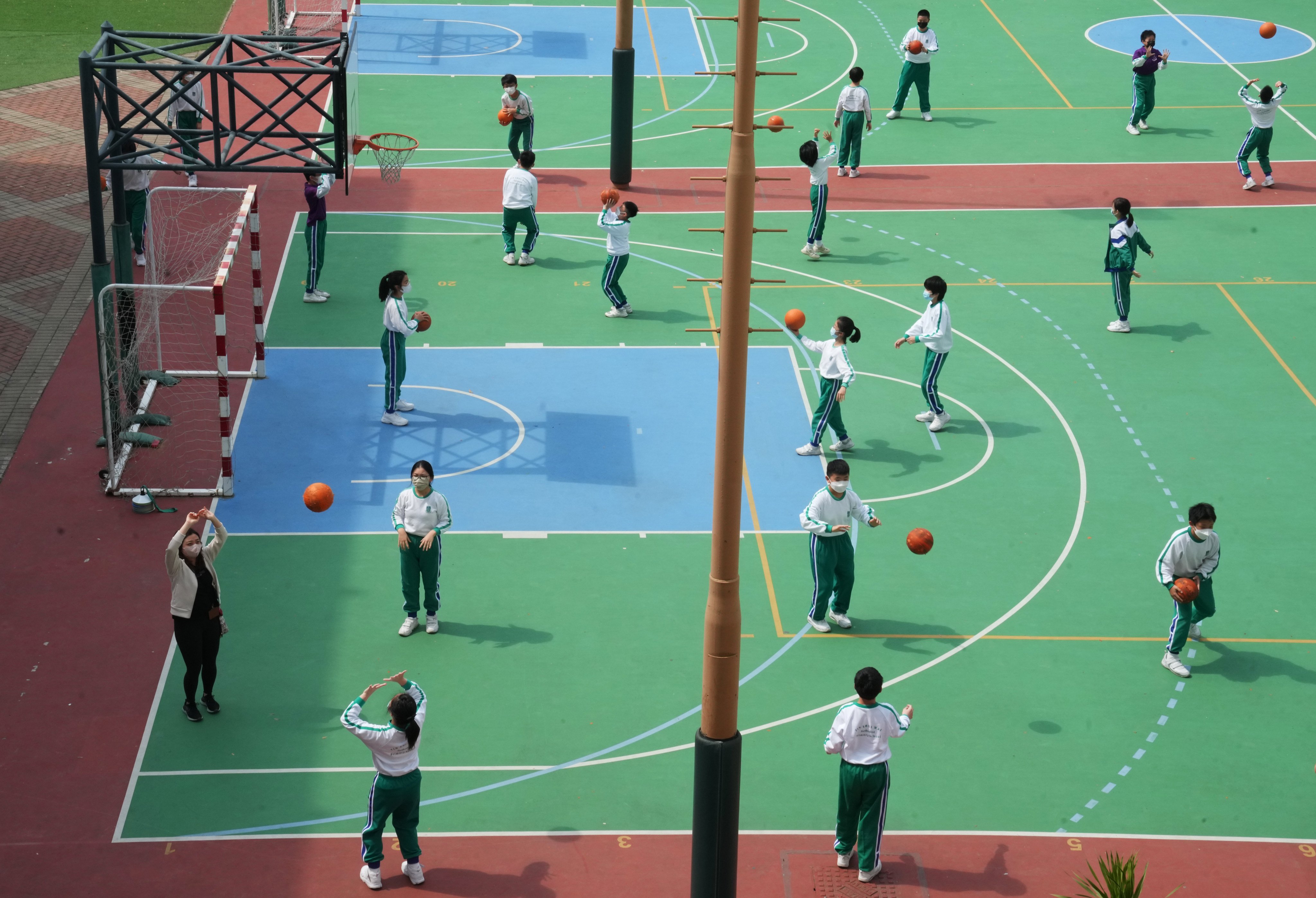 Schoolchildren play basketball at the height of the pandemic with masks on - but a survey has found many have kept wearing them because of worries about their looks. Photo: Sam Tsang