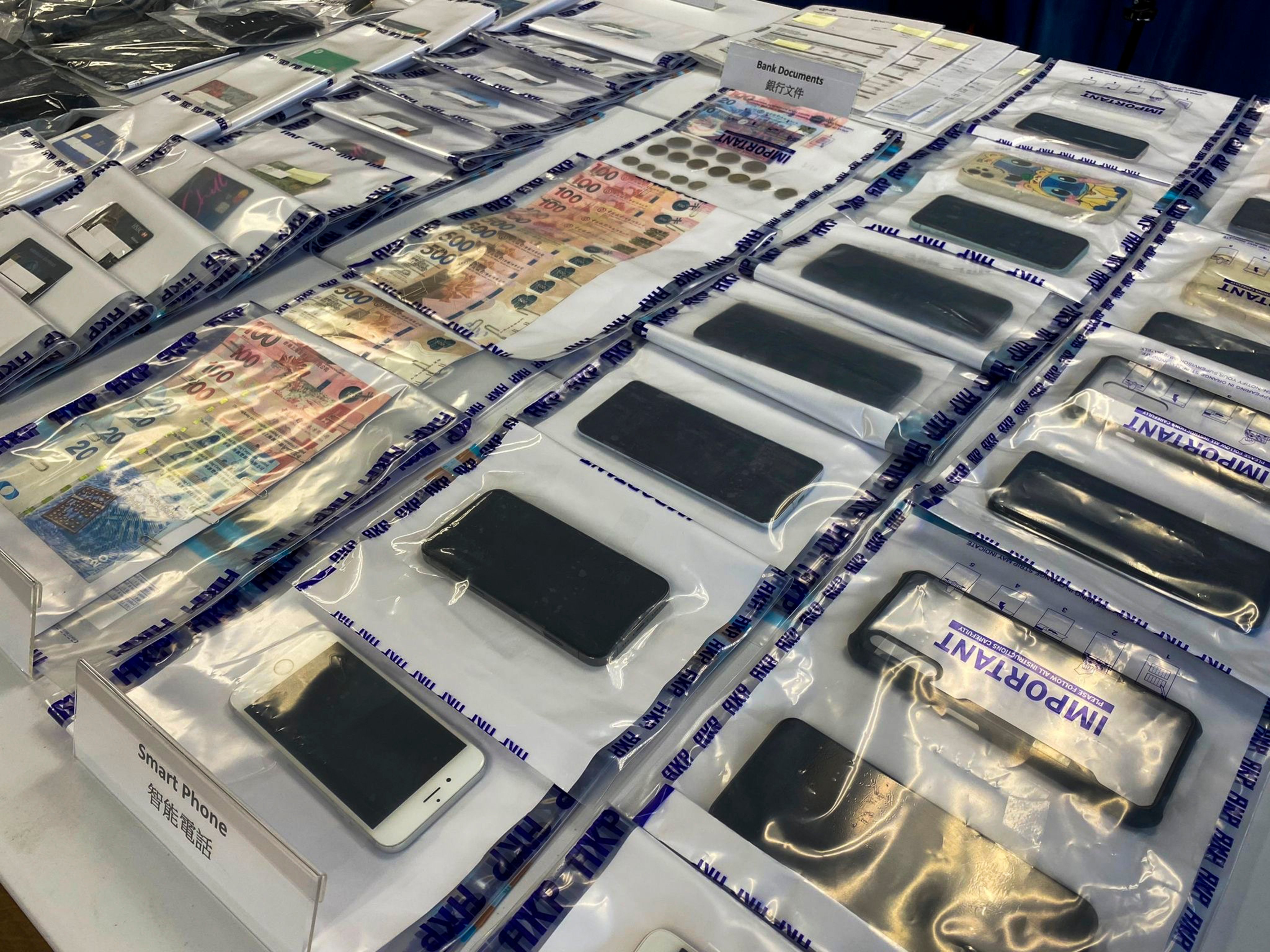 A police display of smartphones and other evidence gathered as part of an anti-deception operation. Photo: Handout