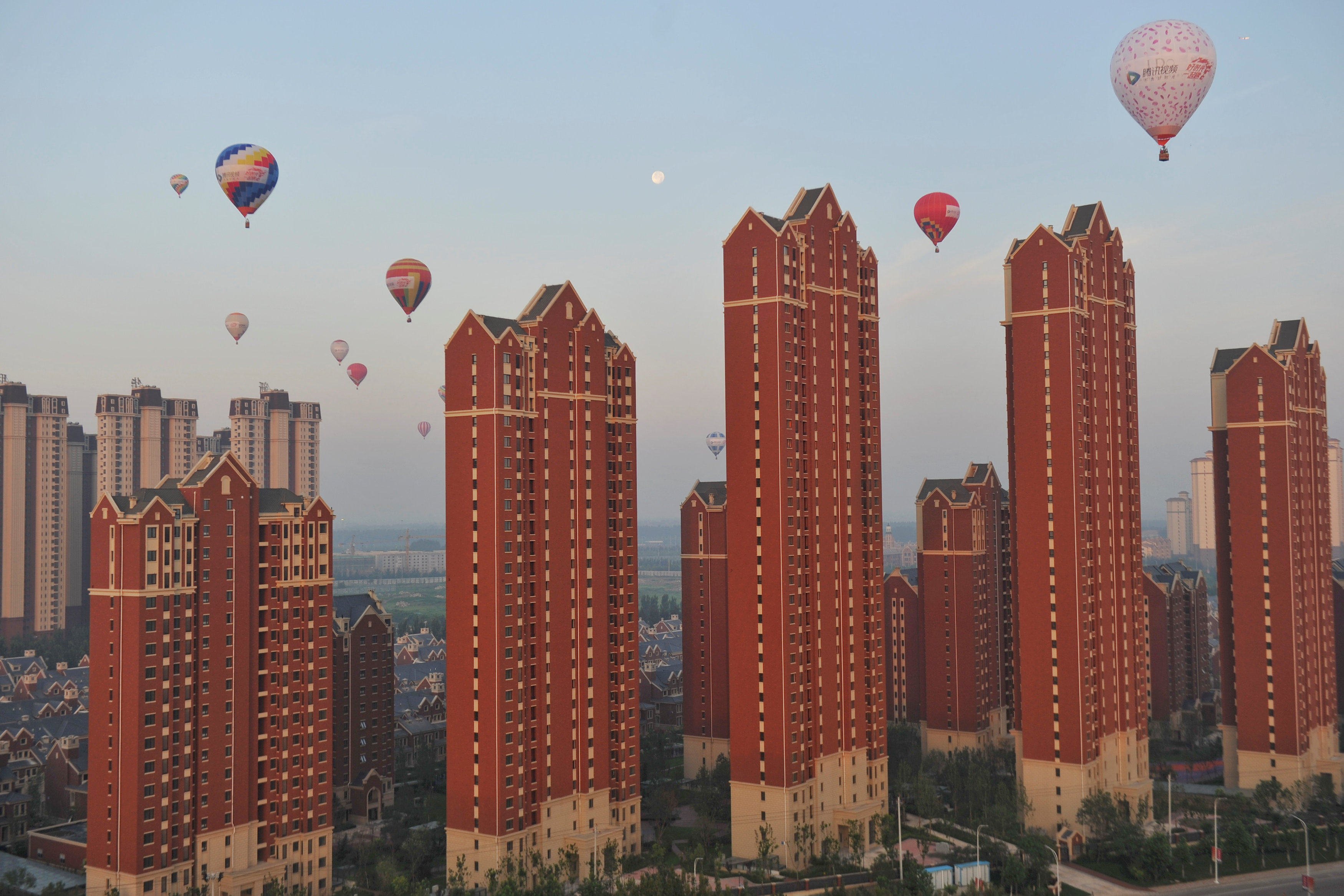 Hot air balloons fly over residential buildings in Wuqing district of Tianjin, China on July 11, 2017. The biggest headwind for domestic demand is the deflation of the property bubble. Photo: Reuters