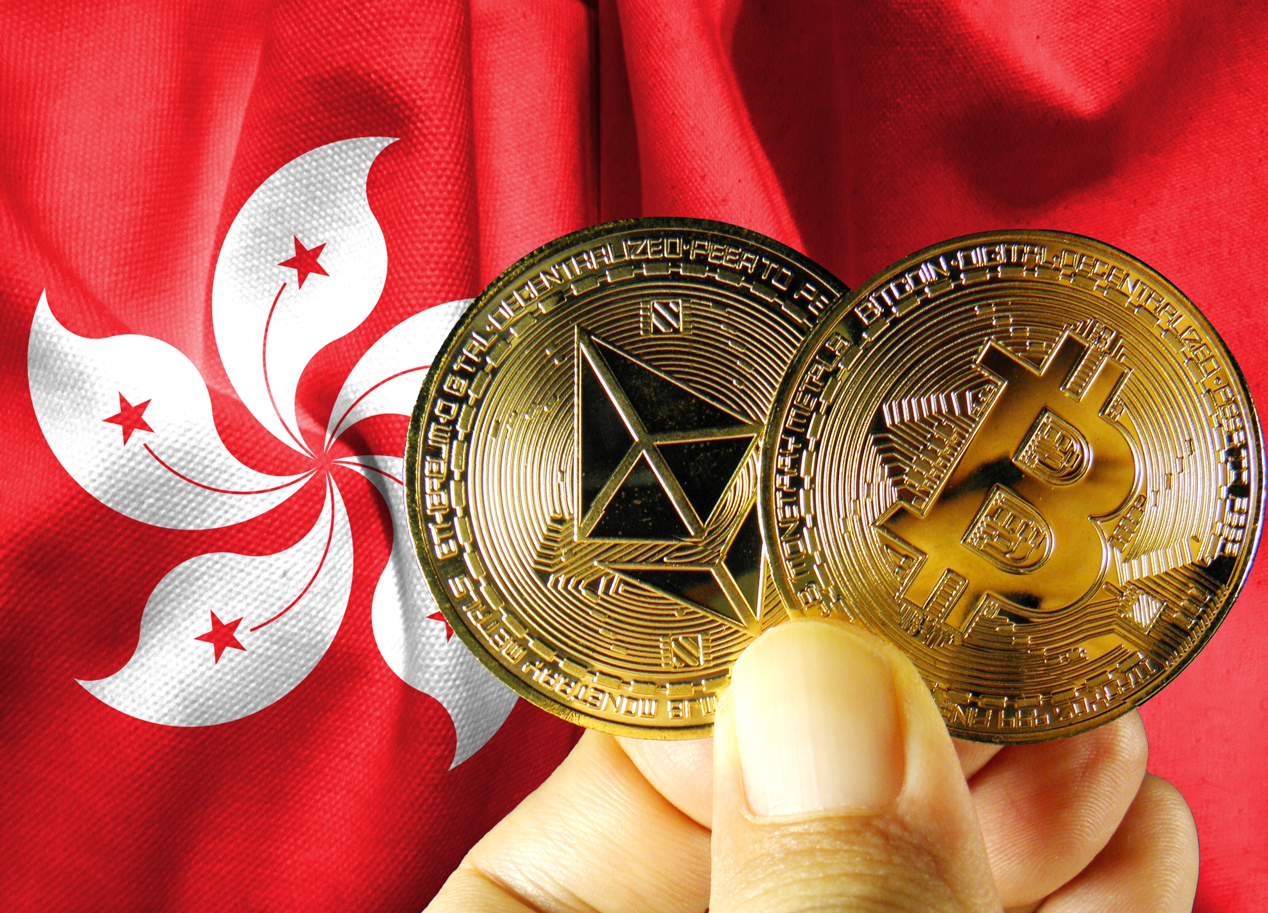 A person holds physical versions of bitcoin against the Hong Kong flag. Photo: Shutterstock Images