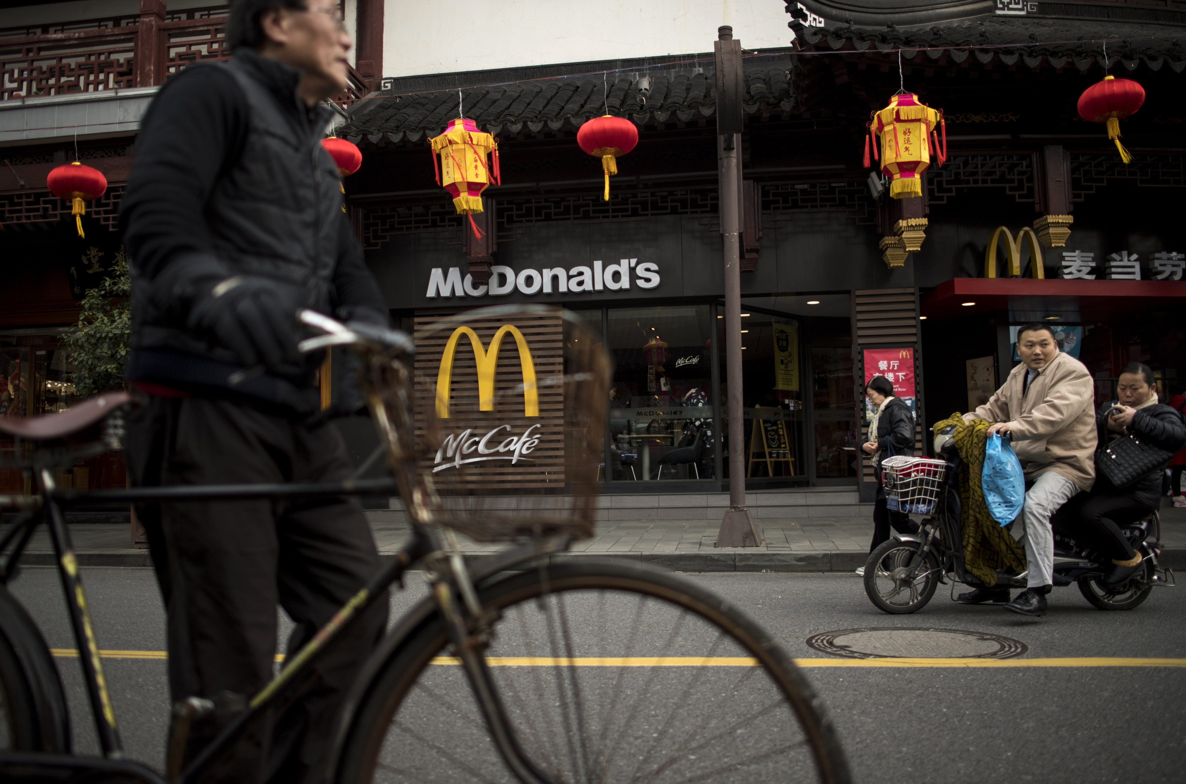 A man pushes his bicycle in front of a McDonald’s fast food restaurant in Shanghai. Photo:AFP