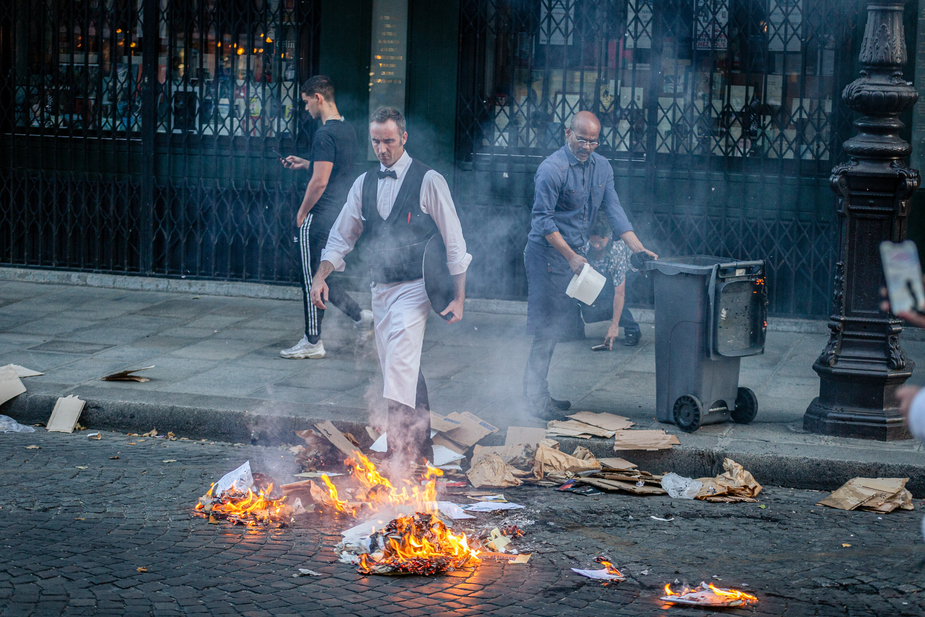Restaurant employees put out a fire started by demonstrators on June 30 in Paris during a protest following the police shooting of a 17-year-old. Photo: dpa 