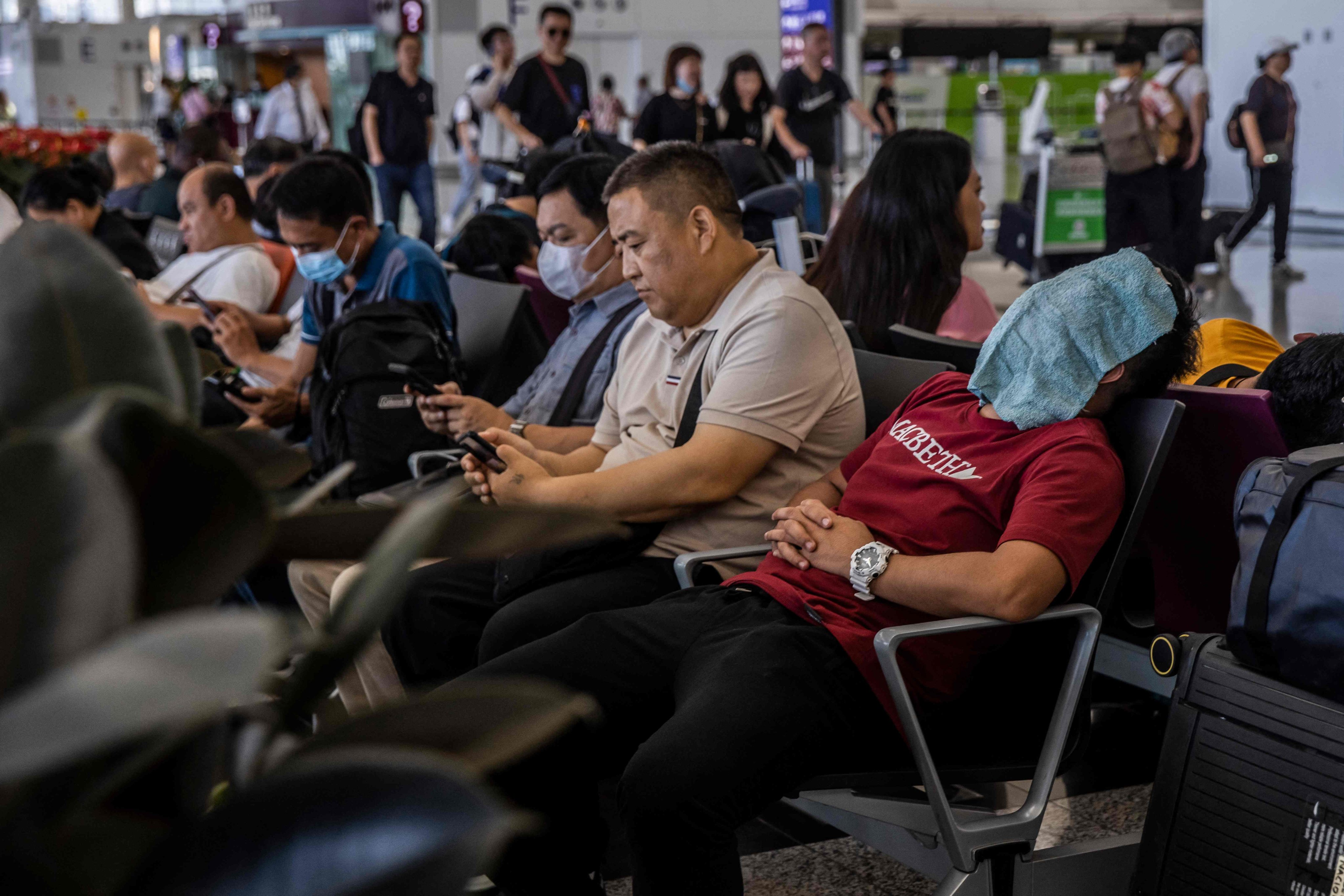 A man sleeps with a towel on his face at Hong Kong International Airport on July 6. Hongkongers’ interest in travel has surged in the aftermath of the Covid-19 pandemic, with travellers planning on leaving the city more often for longer trips and spending more while doing so. Photo: AFP