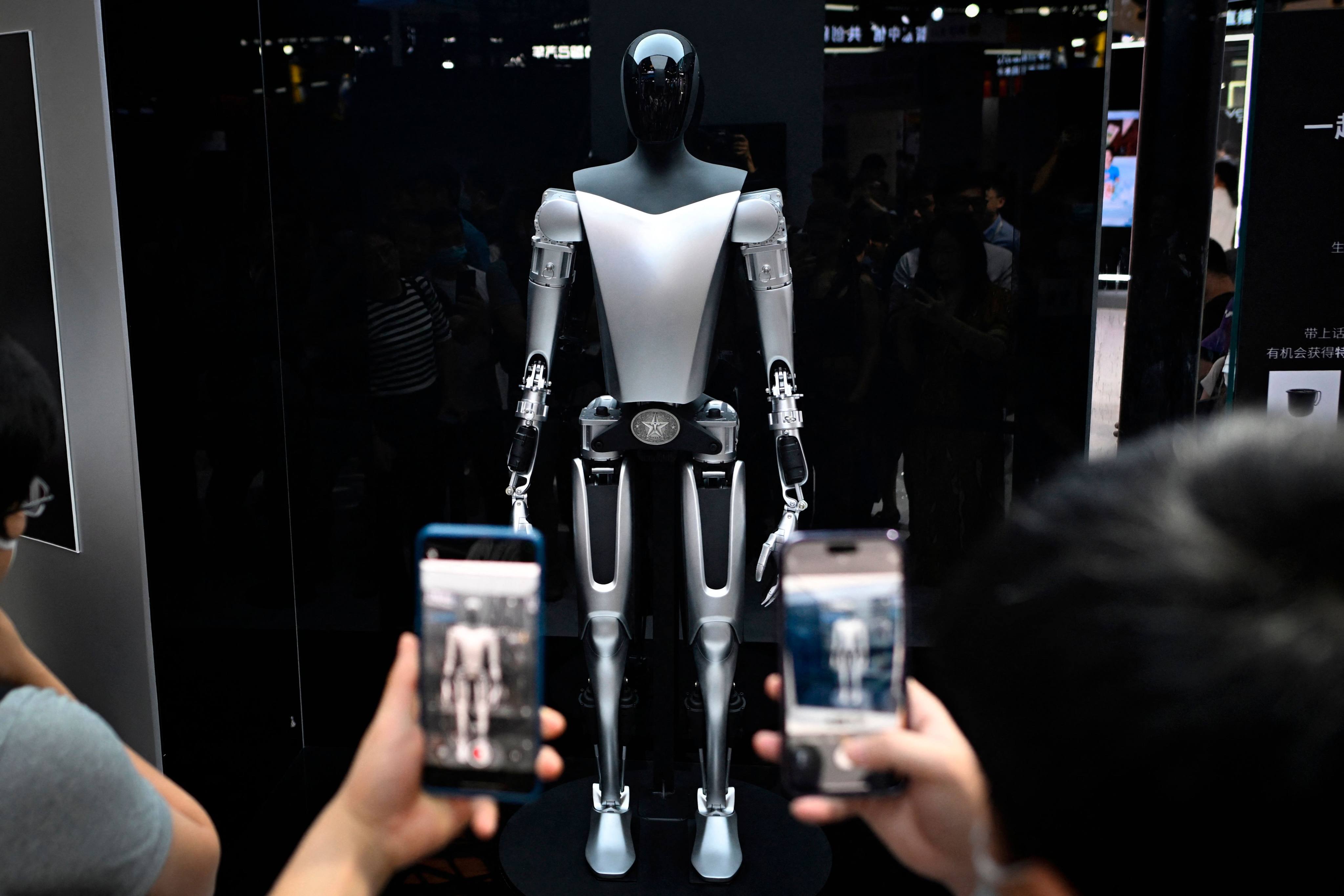 Visitors take photos of a Tesla robot displayed at the World Artificial Intelligence Conference (WAIC) in Shanghai on July 6, 2023. Photo: AFP