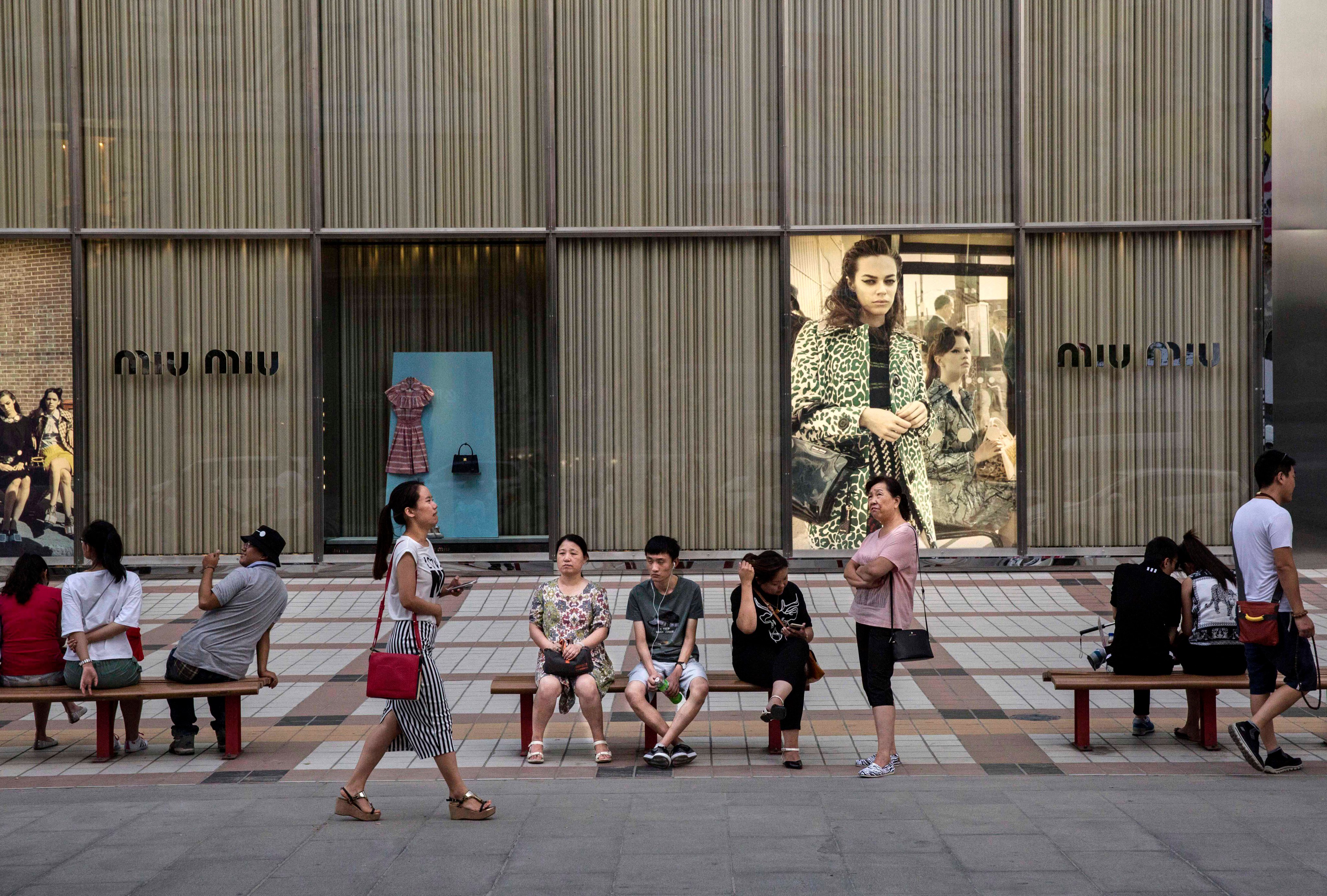 Shoppers sit in front of luxury store Miu Miu in an upscale shopping district in Beijing, China. Photo: Getty Images