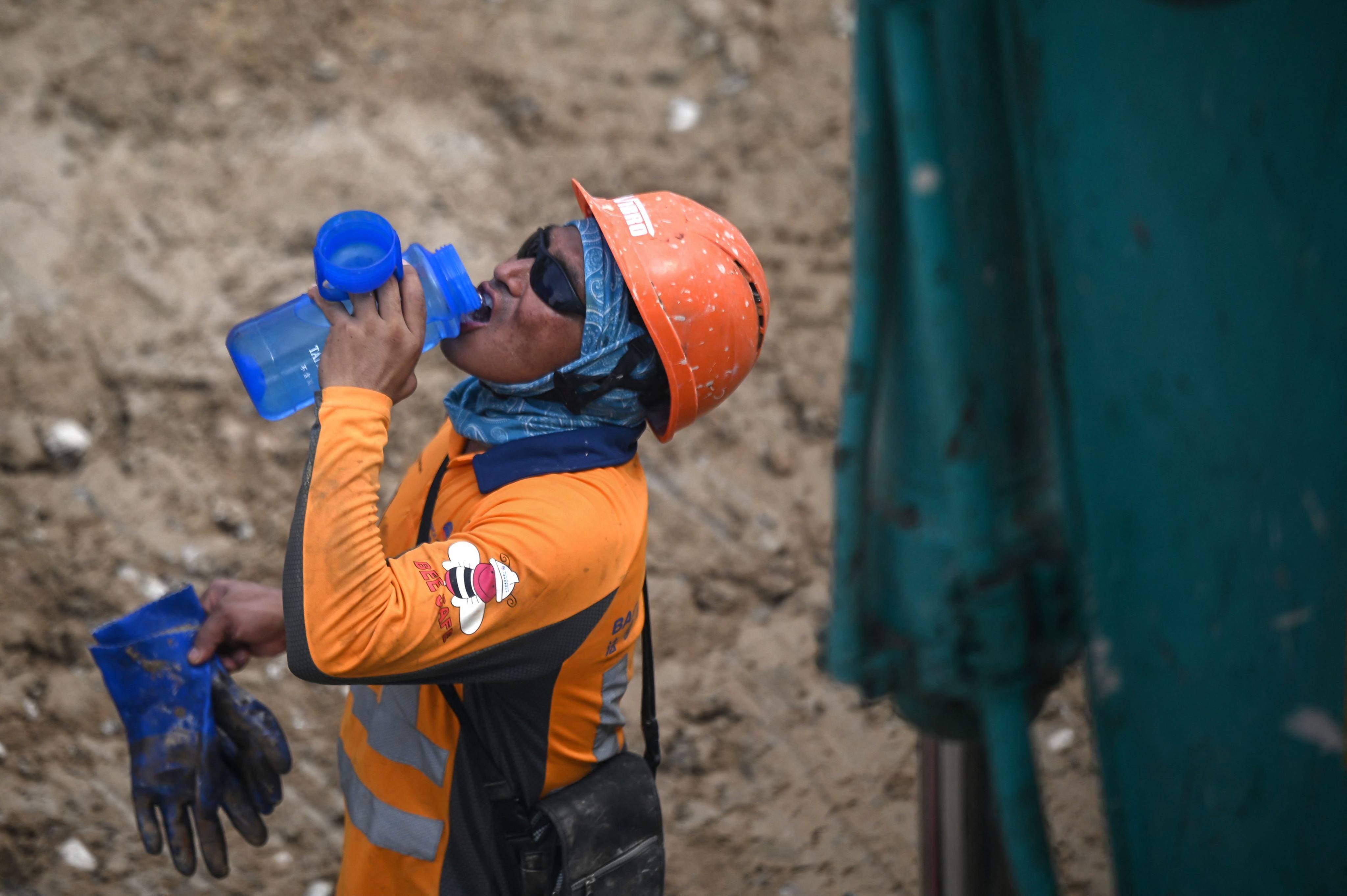 A construction worker in Hong Kong has a drink on June 2, as the government issues a heat warning for outdoor workers with temperatures reaching 35 degrees Celsius. Photo: AFP