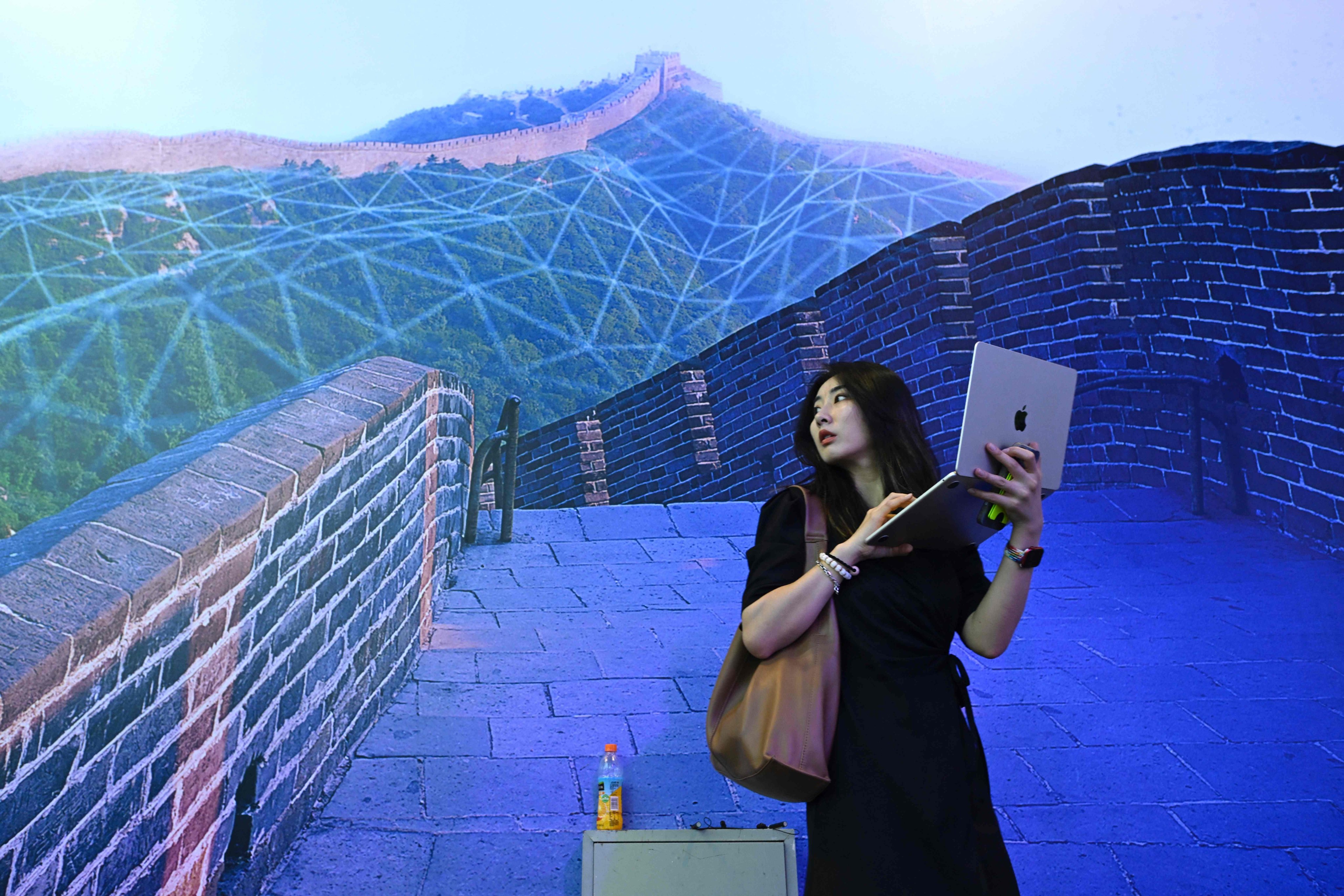 A woman holds up her laptop in front of a poster during the World Artificial Intelligence Conference in Shanghai on July 6. The conference showcased many of the practical benefits of using AI. Photo: AFP