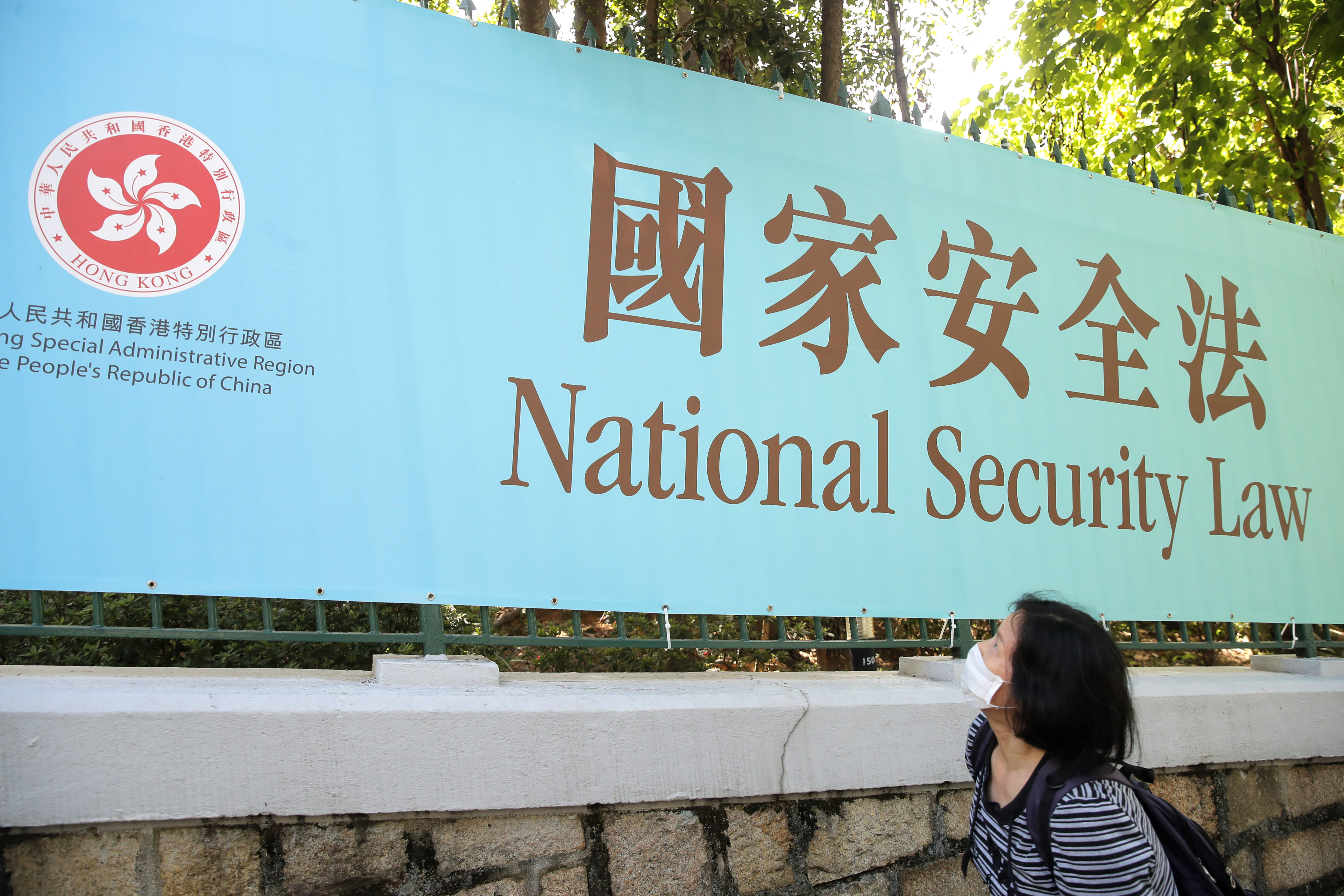 A woman walks past a promotional banner for the Hong Kong national security law in June 2020. Critics have questioned the law’s subsequent effect on the city’s legal system and its business environment. Photo: AP