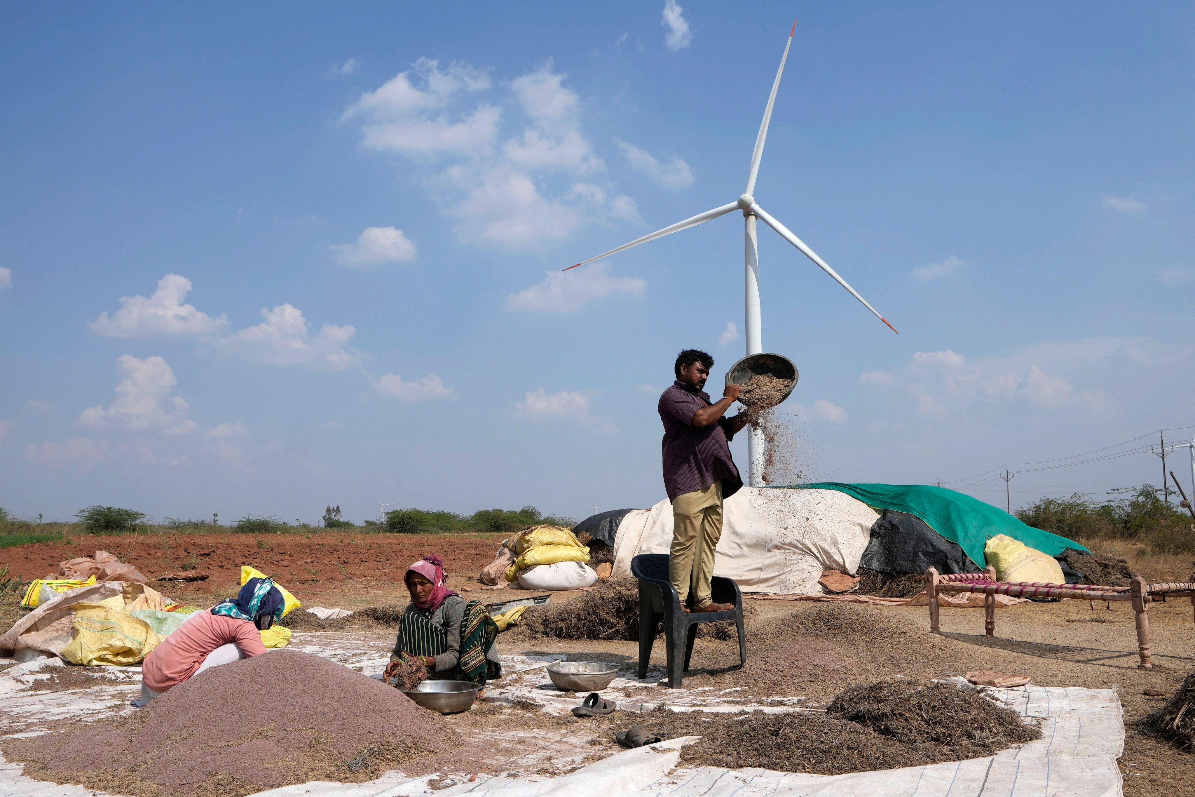 A family works in a field near a wind turbine near Sadla village in Surendranagar district of Gujarat state, in India, on March 20. Most renewable energy investment is focused on rich economies and a small group of developing economies led by Brazil, Vietnam, Chile and India. Photo: AP