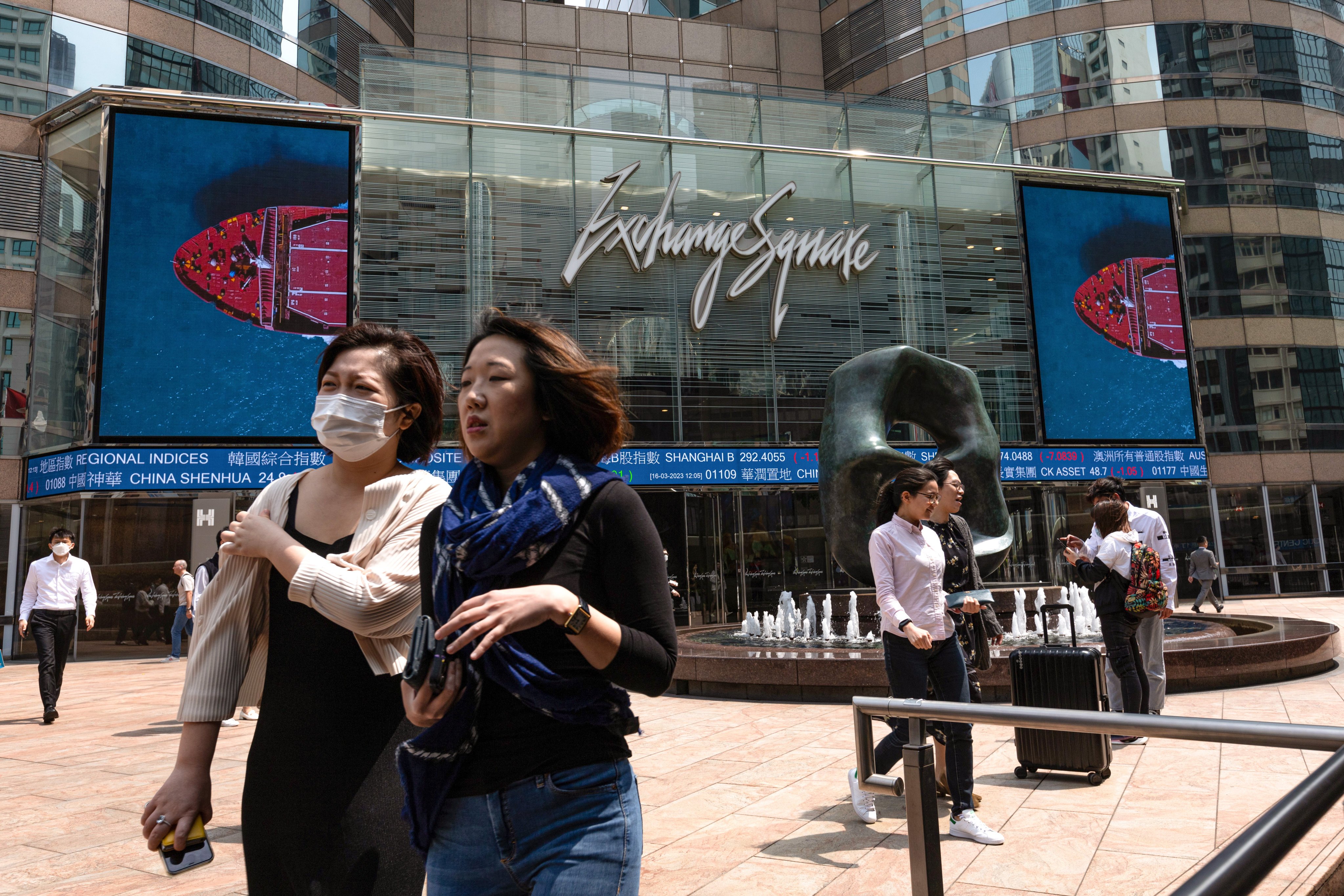 Women walk past a stock ticker outside Exchange Square, the building housing the stock exchange, in Hong Kong, on March 16. The city has an opportunity to seek out more women to join the workforce. Photo: EPA-EFE