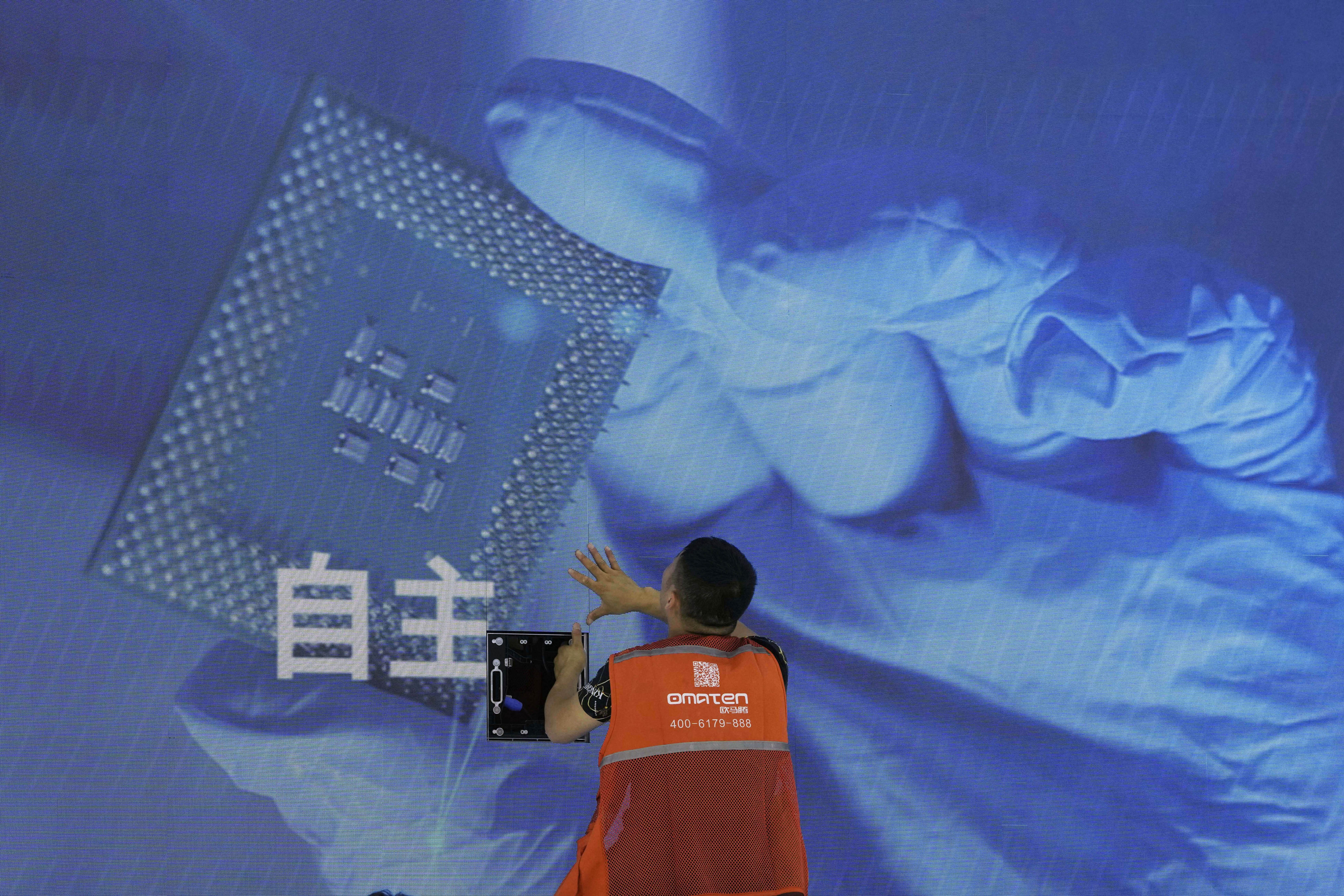 A worker stands in front of a display showing a computer chip and the Chinese word for “independence”. Photo: AP Photo