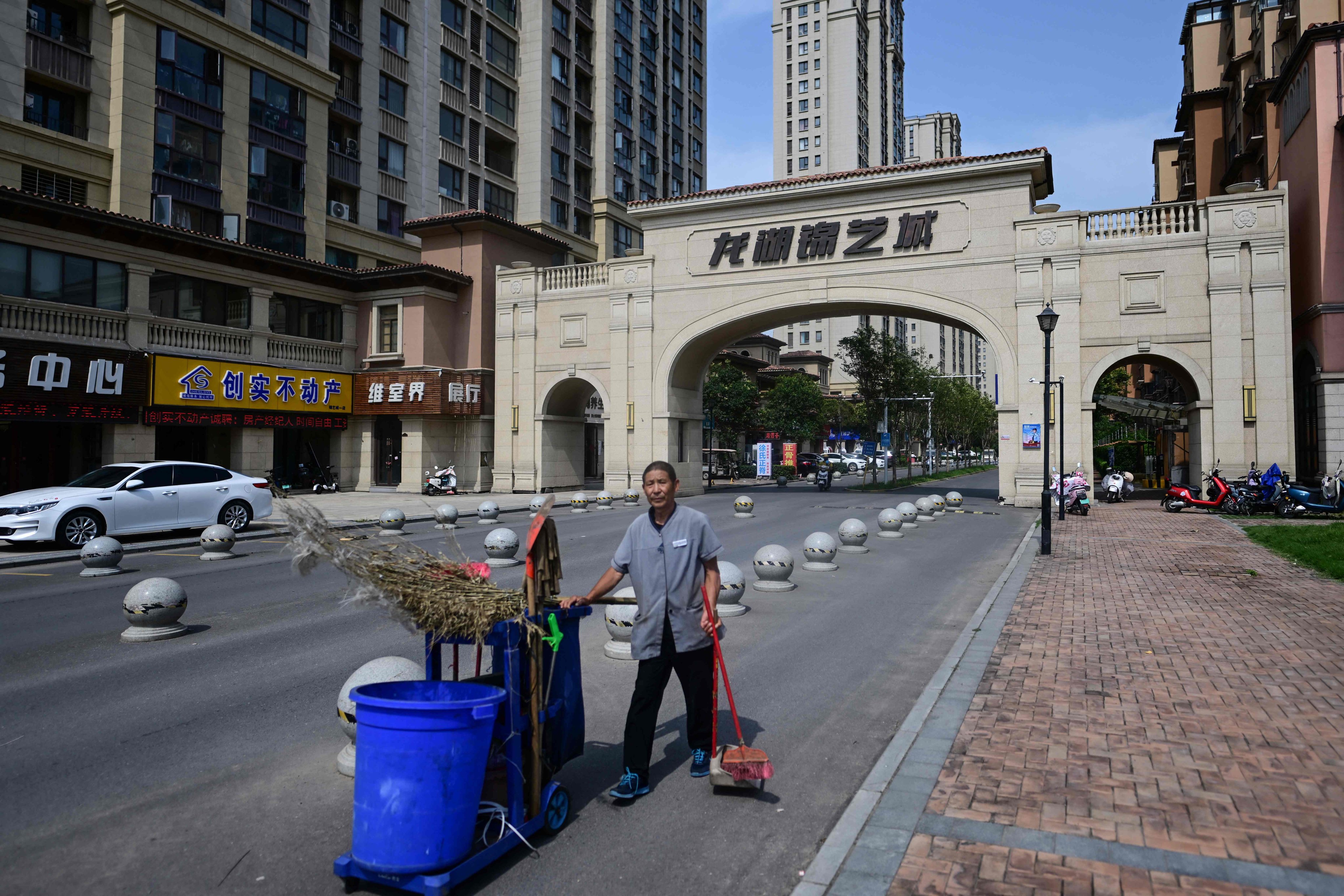 A cleaner walks through a complex of unfinished flats in Xinzheng City, in Zhengzhou, Henan province, on June 20. The continued struggles of China’s property sector are among several factors driving hopes of more aggressive stimulus measures. Photo: AFP