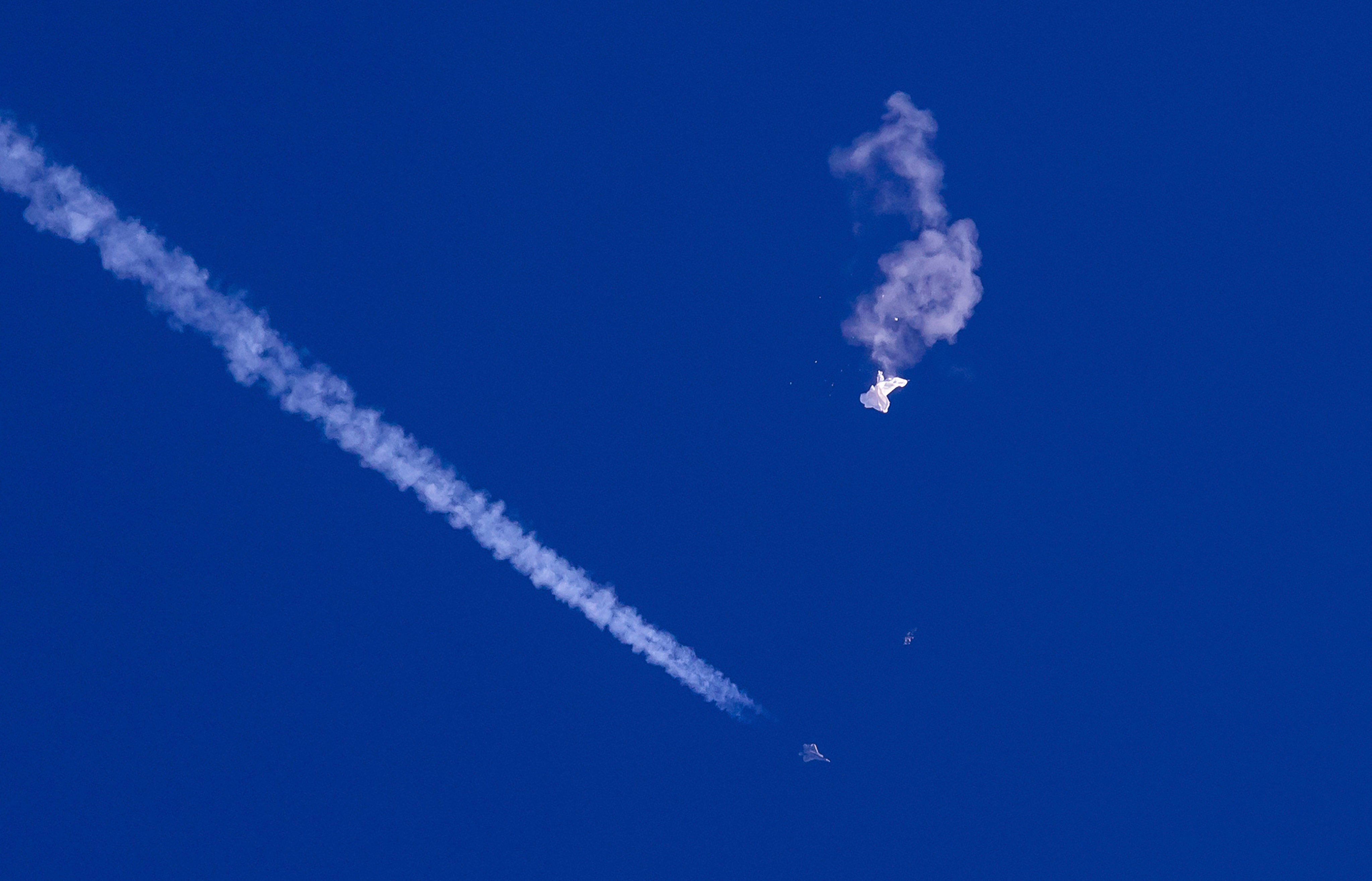 A fighter jet flies past the remnants of a large balloon falling into the Atlantic Ocean after it was shot down just off the coast of South Carolina on February 4, 2023. Photo: AP 