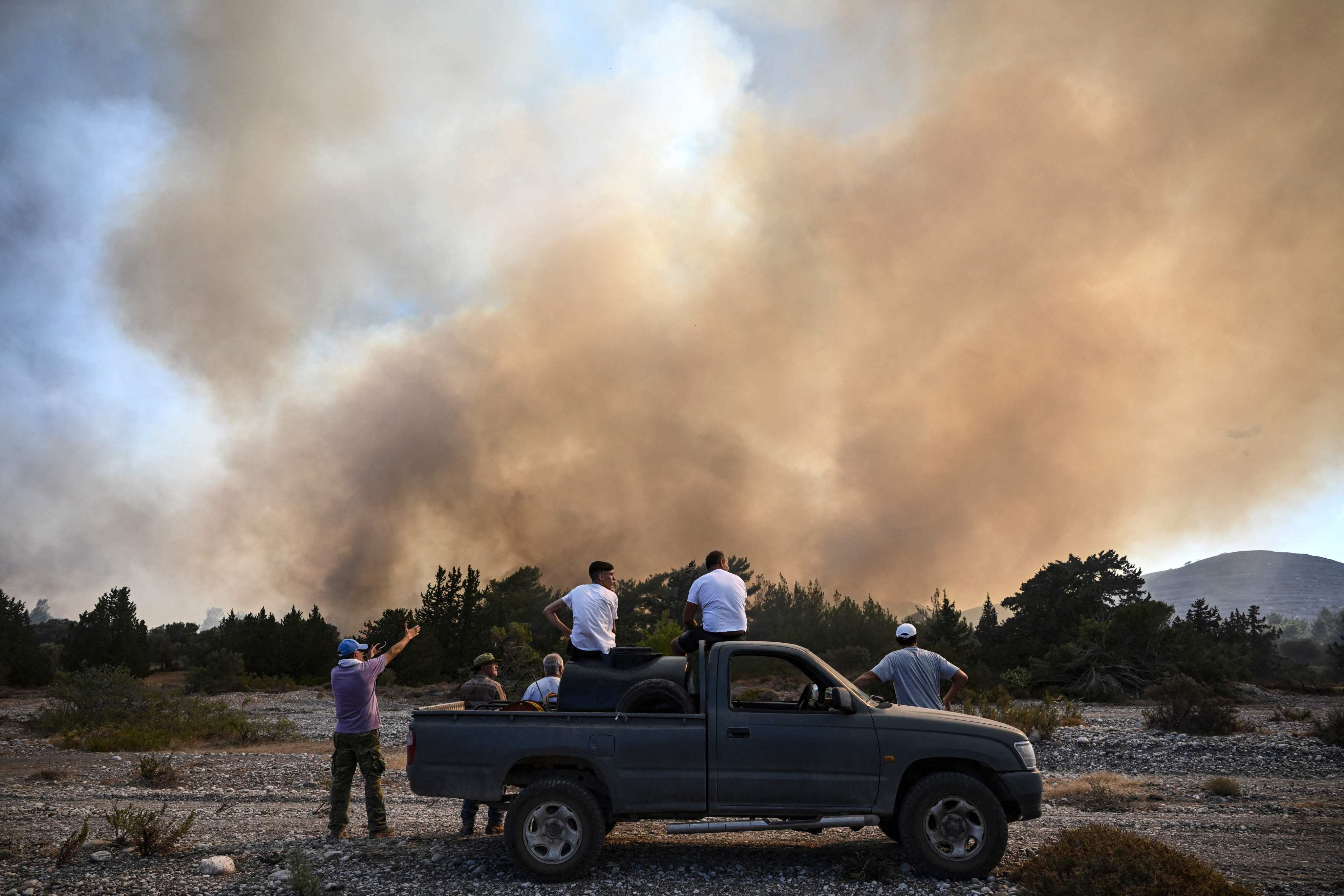 People watch wildfires close to the village of Vati on the Greek island of Rhodes on July 25. Some 30,000 people fled over the weekend in the country’s largest-ever wildfire evacuation. Photo: AFP