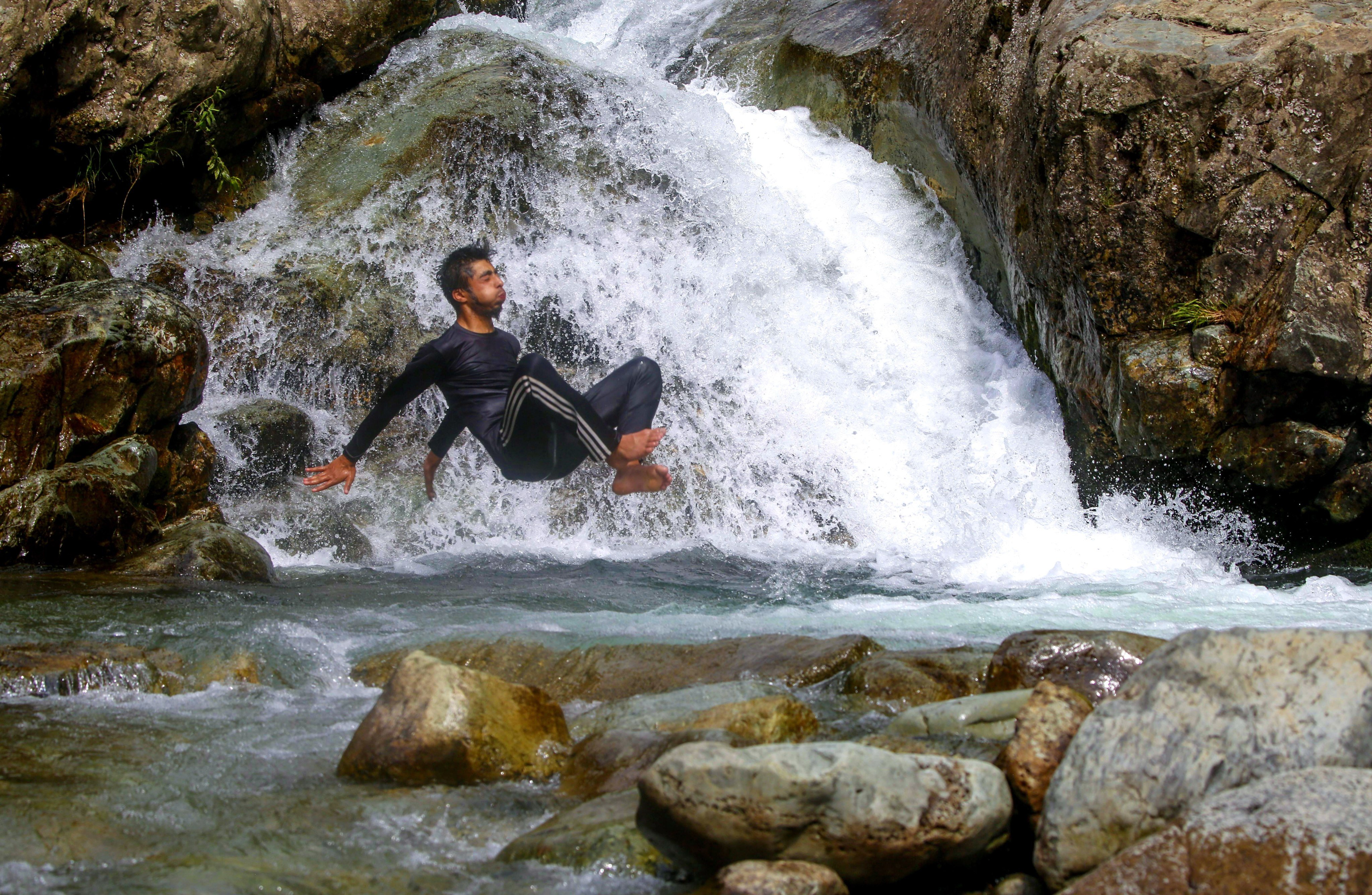 A Kashmiri teenager jumps into a stream to beat the heat on the outskirts of Srinagar, India, on July 5. Photo: EPA-EFE