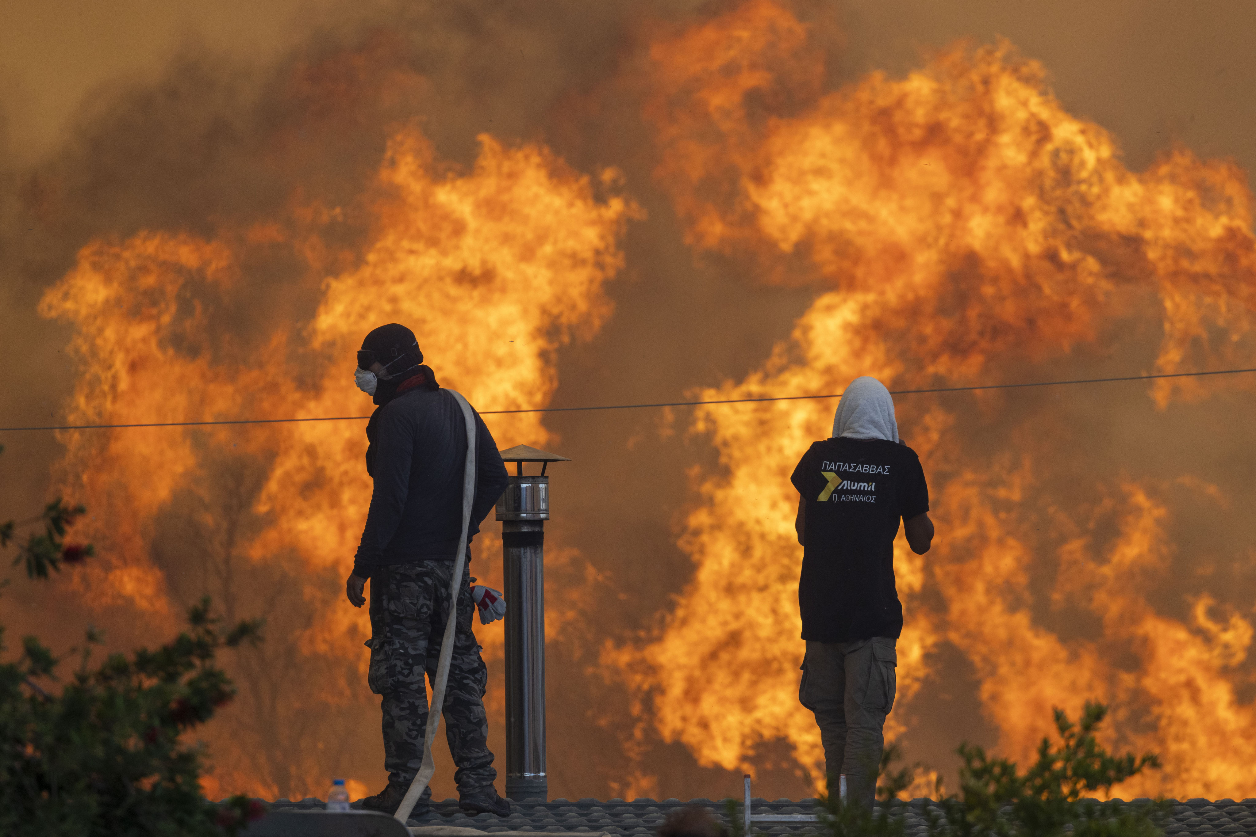 Residents stand on their roofs on July 25 in front of huge flames in the Greek village of Gennadi during forest fires on the island of Rhodes. Several regions across Greece are still on high alert. Photo: dpa