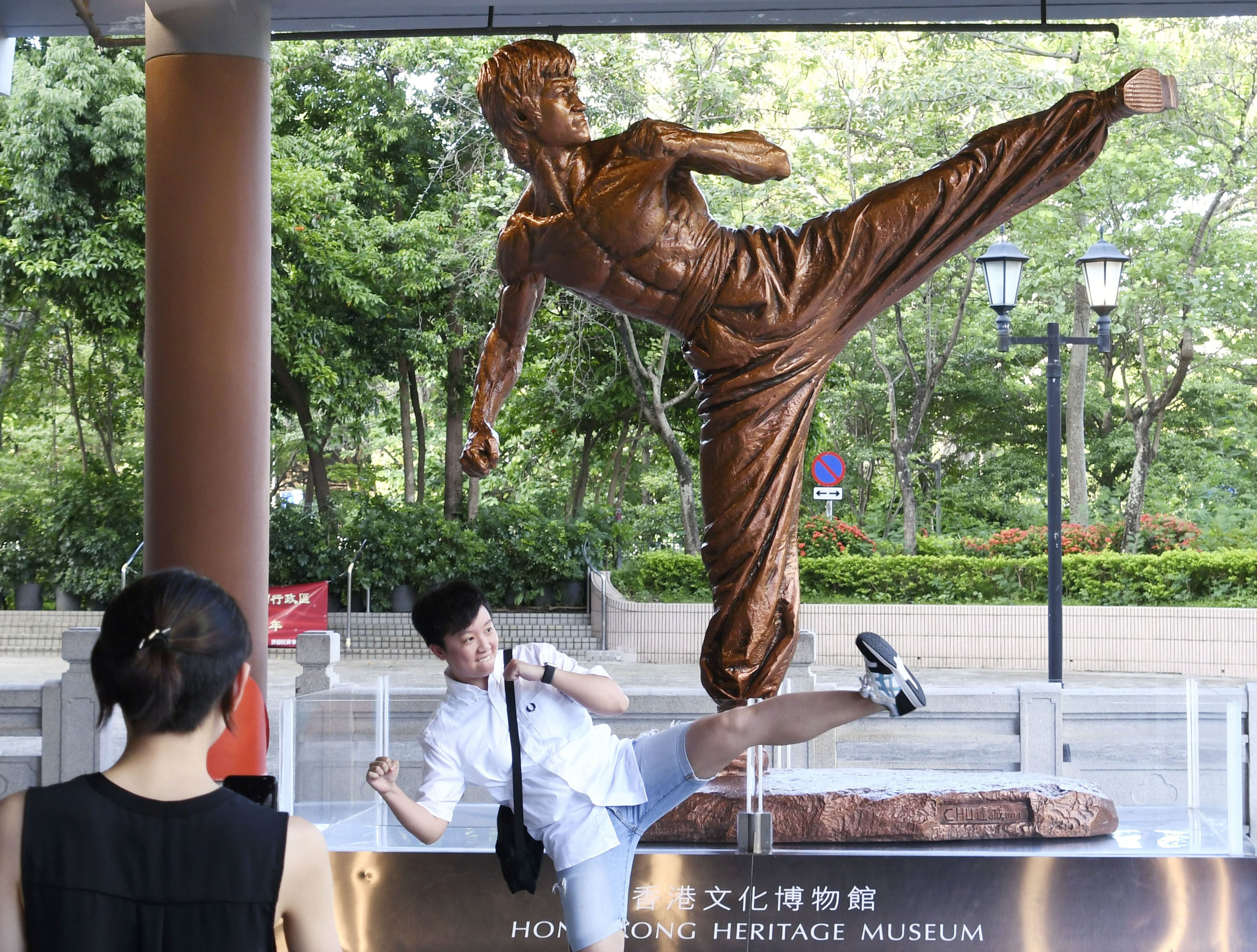 A visitor imitates Bruce Lee in front of a statue of the kung fu legend at the Hong Kong Heritage Museum in Hong Kong. Photo: Kyodo