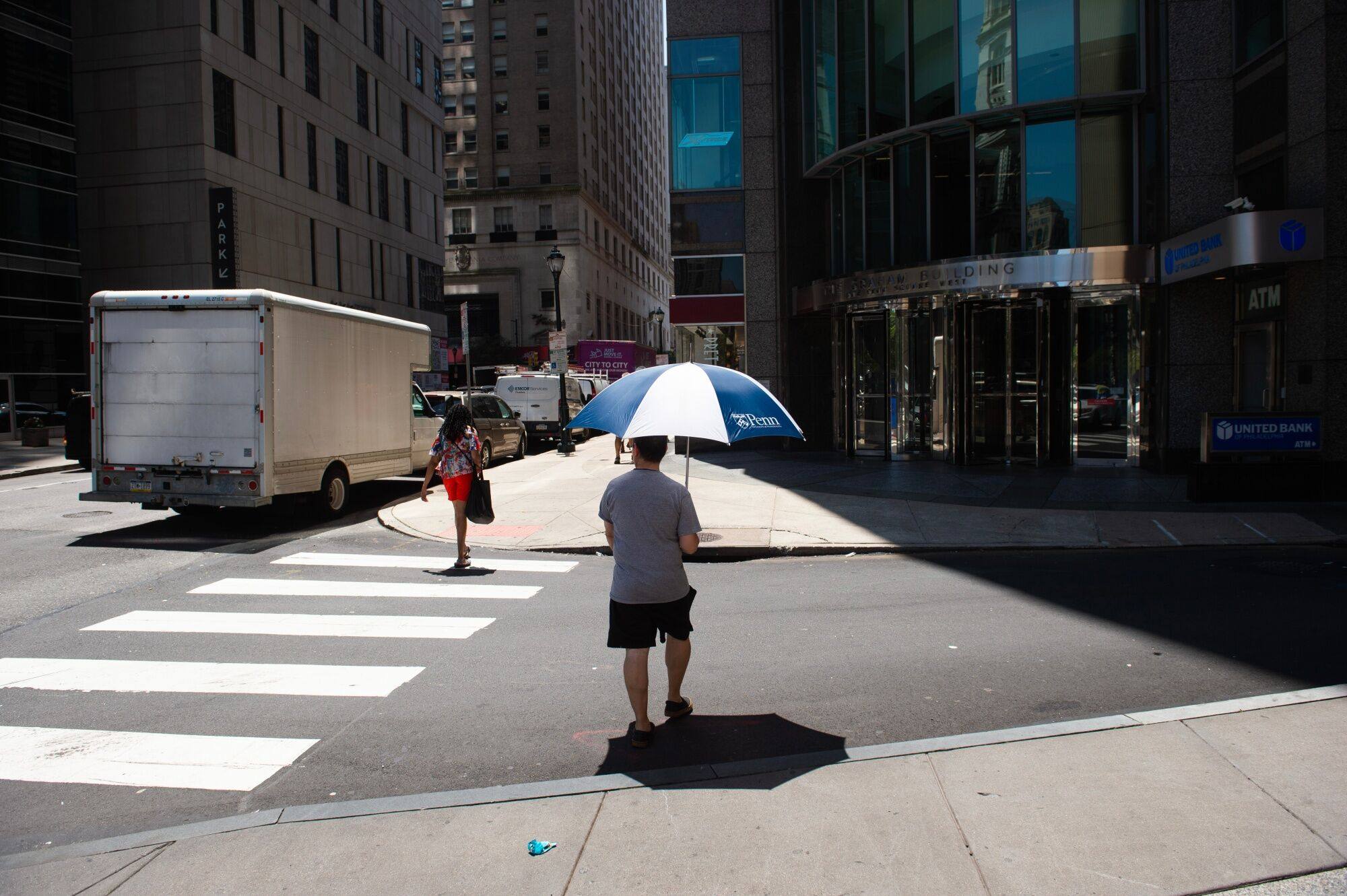 A pedestrian carries an umbrella to shade himself from the sun during a heatwave in Philadelphia, US, on July 28. The signs of a climate crisis should push us to seriously examine our unquestioned acceptance of economic growth as a public good. Photo: Bloomberg