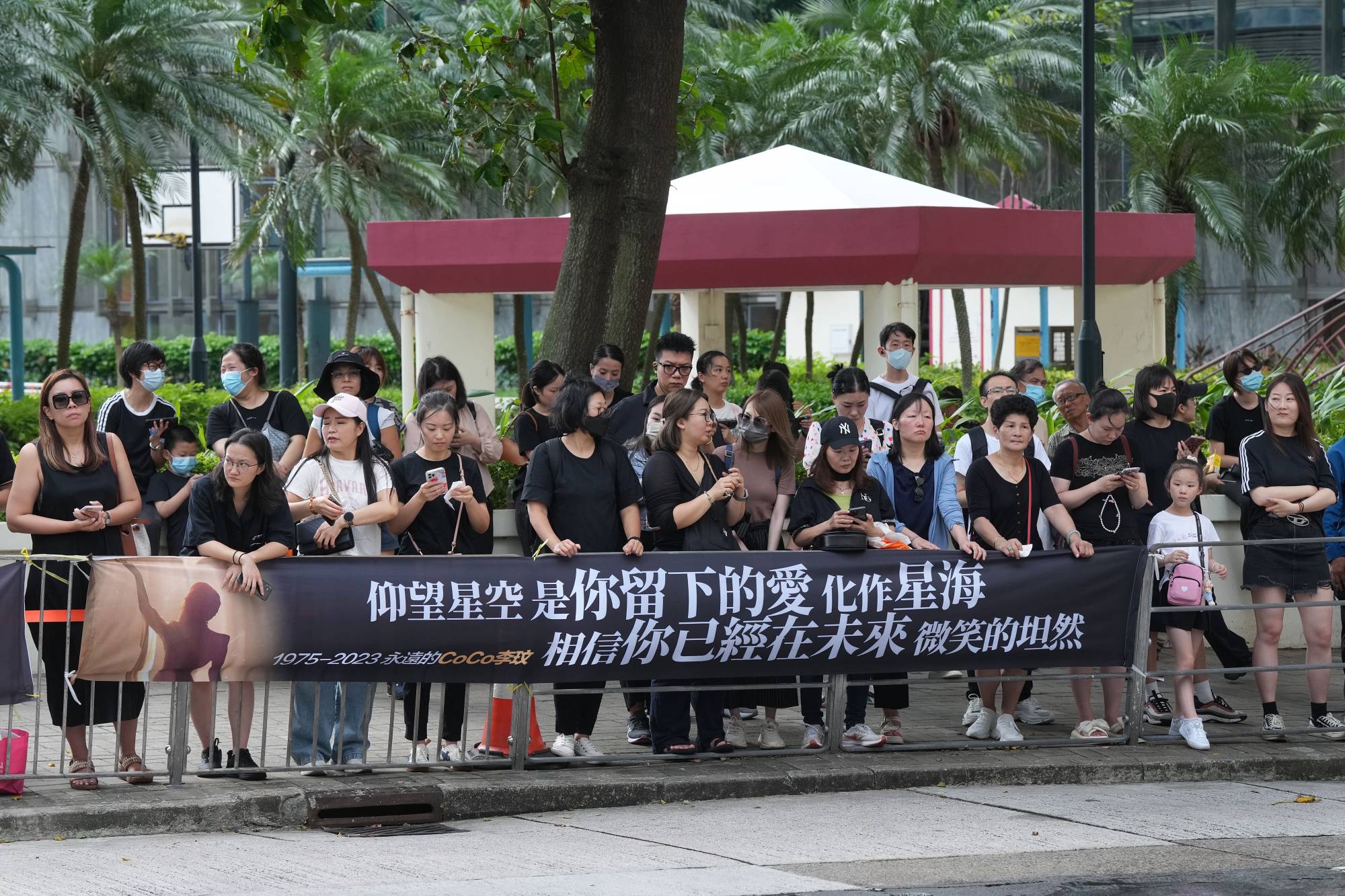 Fans on the road opposite the funeral home hang a banner paying tribute to Coco Lee. Photo: Elson Li