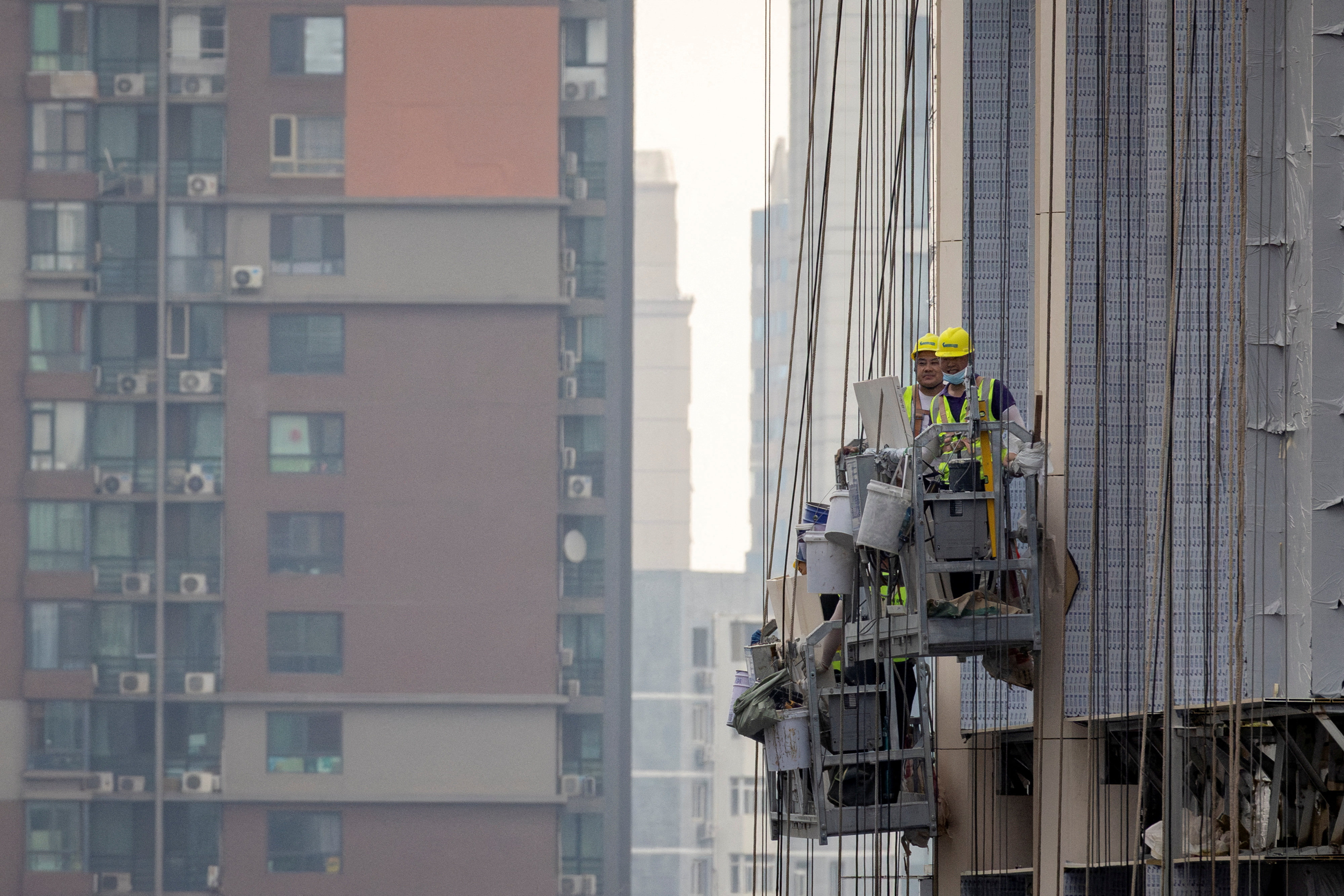 Workers hang off the side of the construction site of a block of flats in Beijing on July 29. Turmoil in the housing market is one of several factors raising concerns about the state of China’s economy. Photo: Reuters