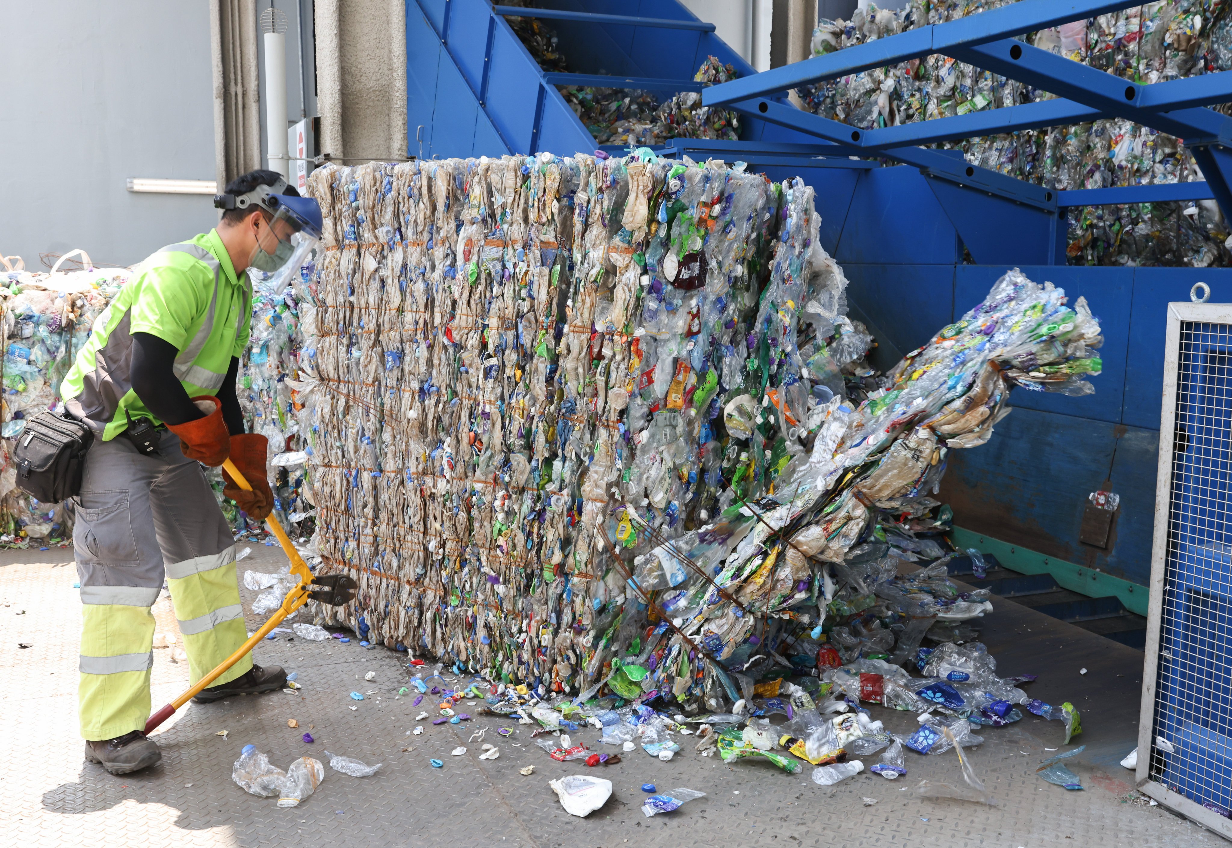 A worker transfers recycled plastic bottles to a bale breaker at New Life Plastics’ facility at EcoPark at Tuen Mun on September 6, 2022. The plant ceased operations in April after consistently running well below capacity because there were not enough plastic bottles to recycle. Photo: K.Y. Cheng
