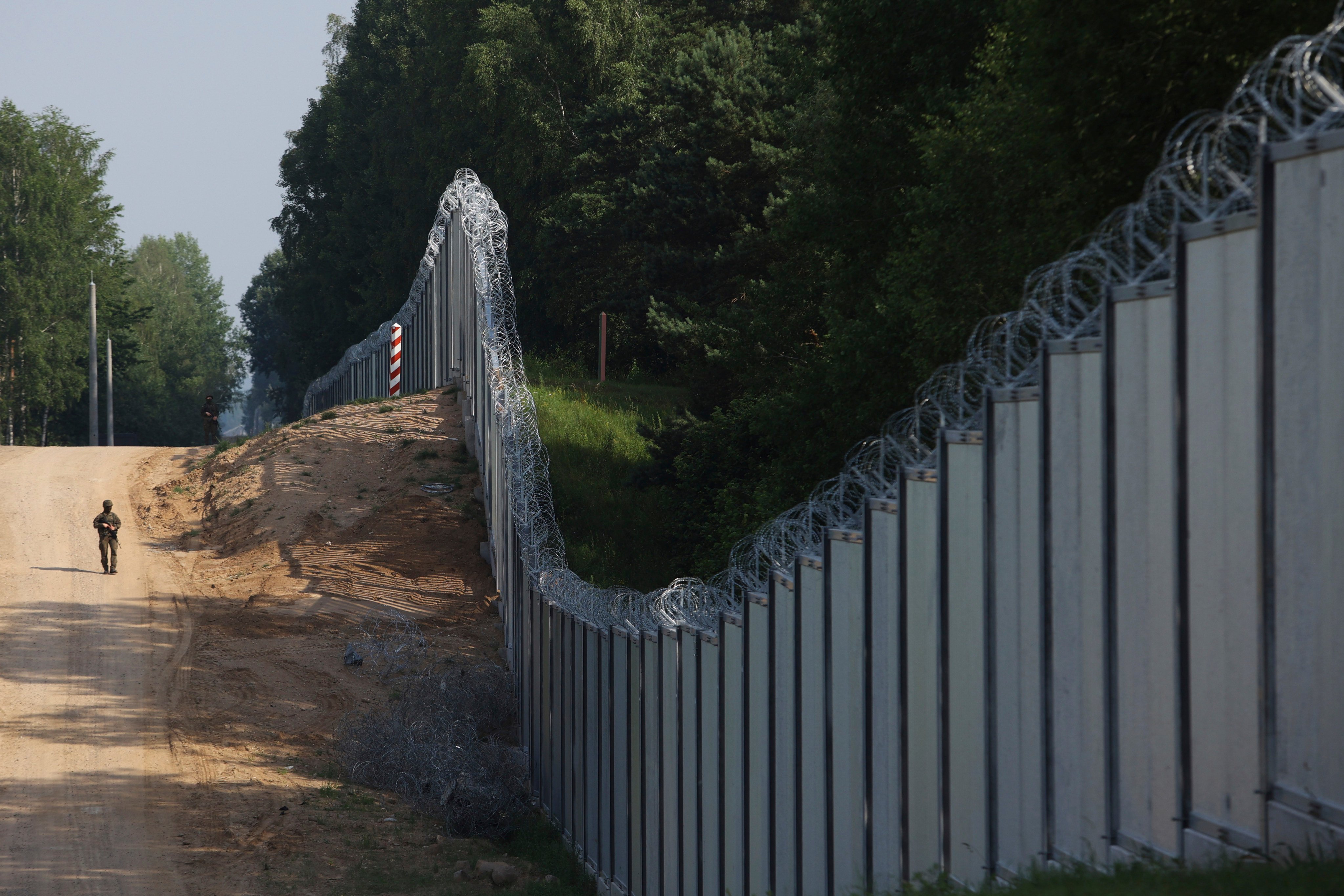 A Polish border guard patrols a metal wall on the border between Poland and Belarus in June. Photo: AP