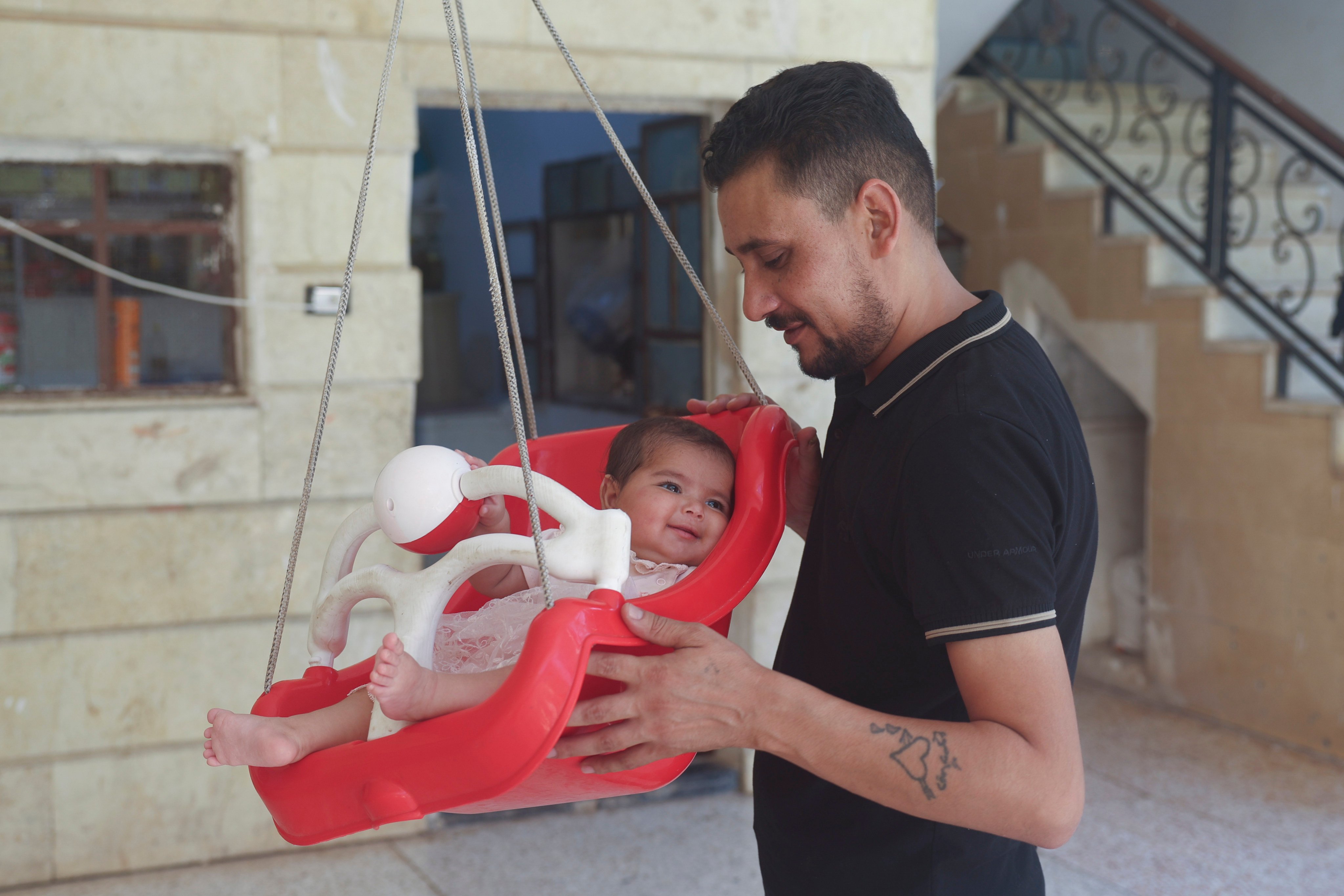 Khalil al-Sawadi plays with his adopted daughter Afraa in Jinderis, Syria, on Saturday. Photo: AP