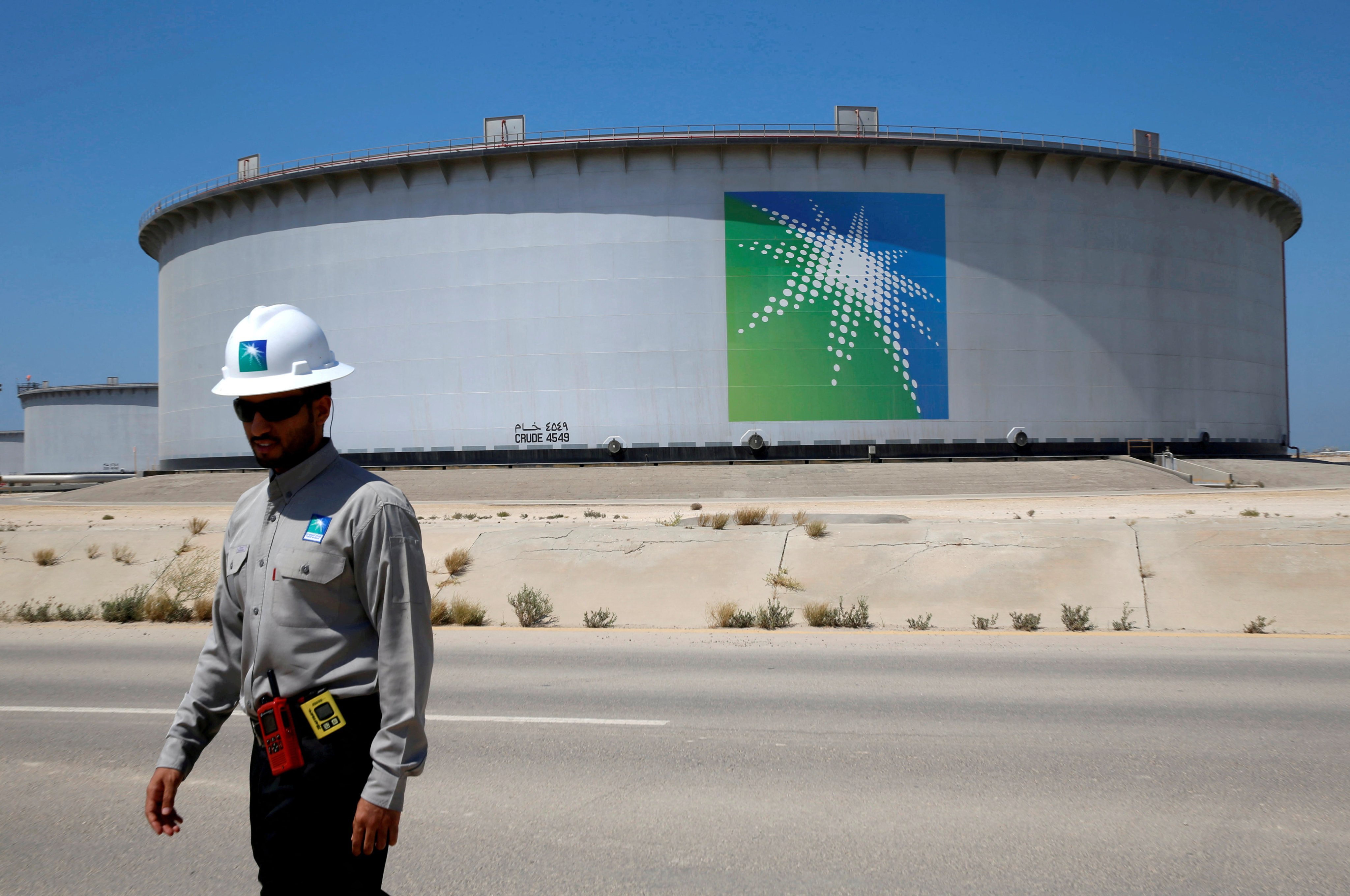 An Aramco employee walks near an oil tank at the company’s Ras Tanura refinery and storage terminal in Saudi Arabia. Photo: Reuters