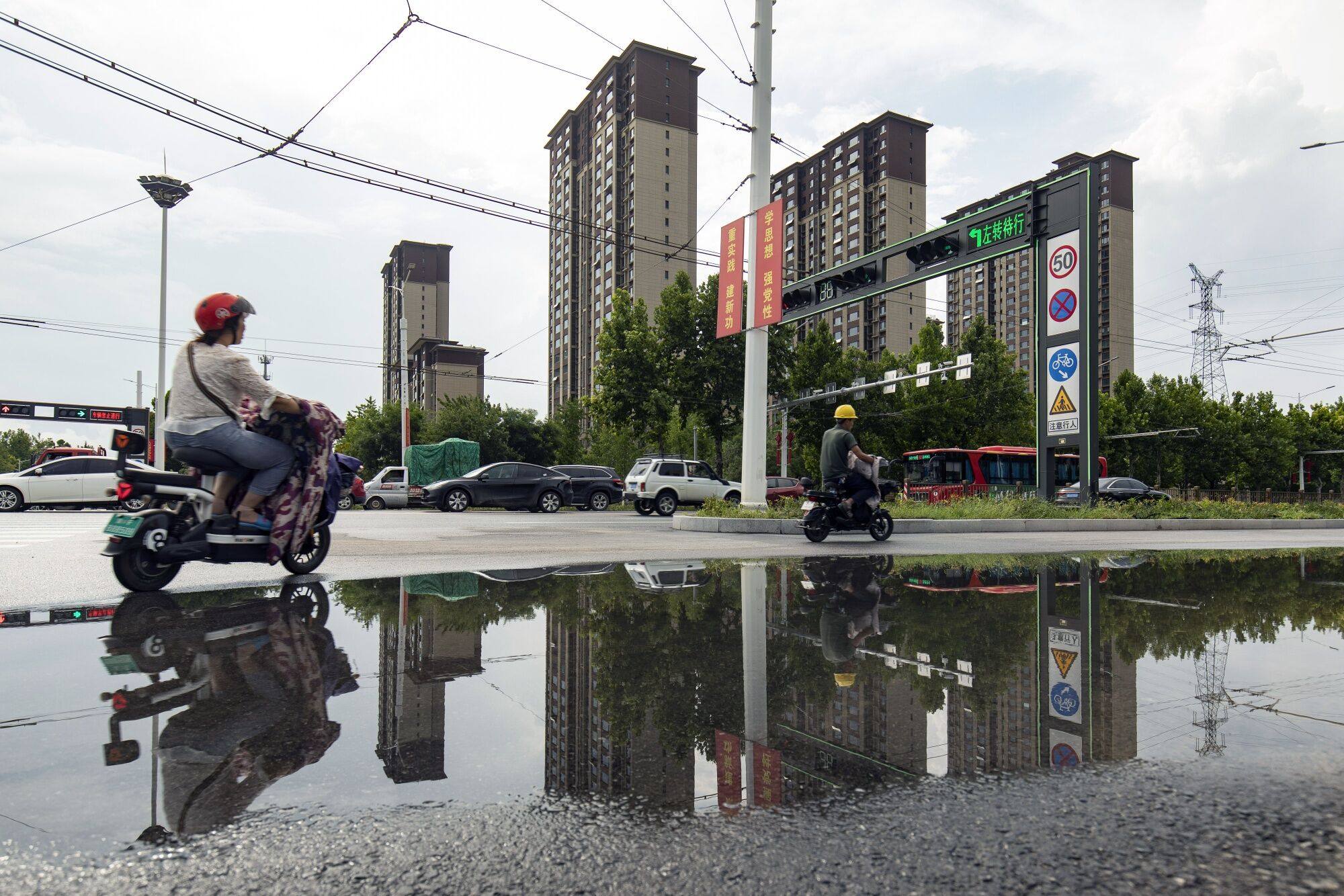 Moped riders pass residential buildings developed by Country Garden Holdings in Baoding, Hebei province, on August 1. Housing has become unaffordable for many young people in China. Photo: Bloomberg