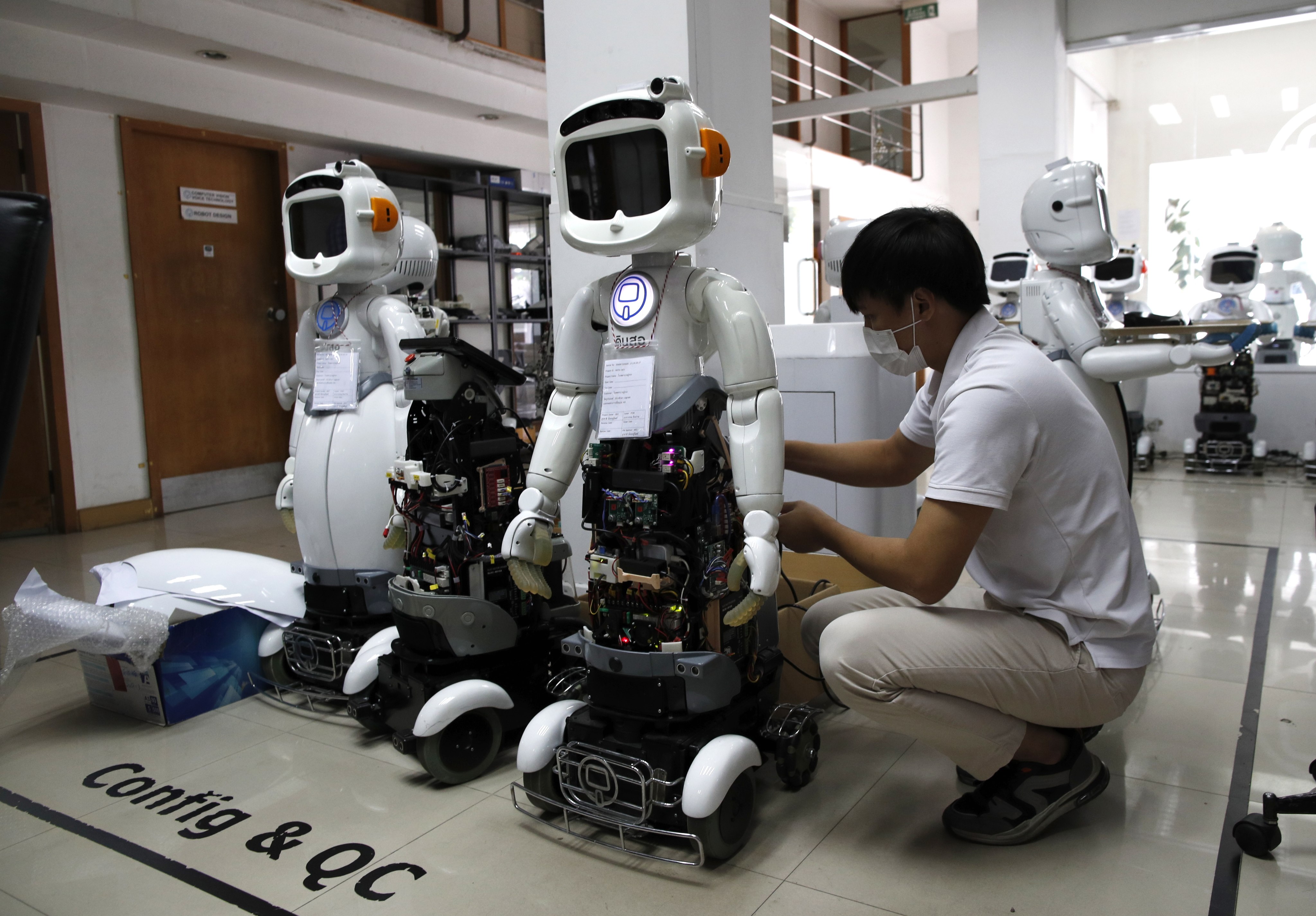A technician sets up Dinsaw robots designed for healthcare and service businesses at CT Asia Robotics in Bangkok on July 24. The Dinsaw Mini 3 combines three artificial intelligence which can communicate with people, such as by offering medication reminders, and alert health emergencies to carers in case of unusual activity. Photo: EPA-EFE