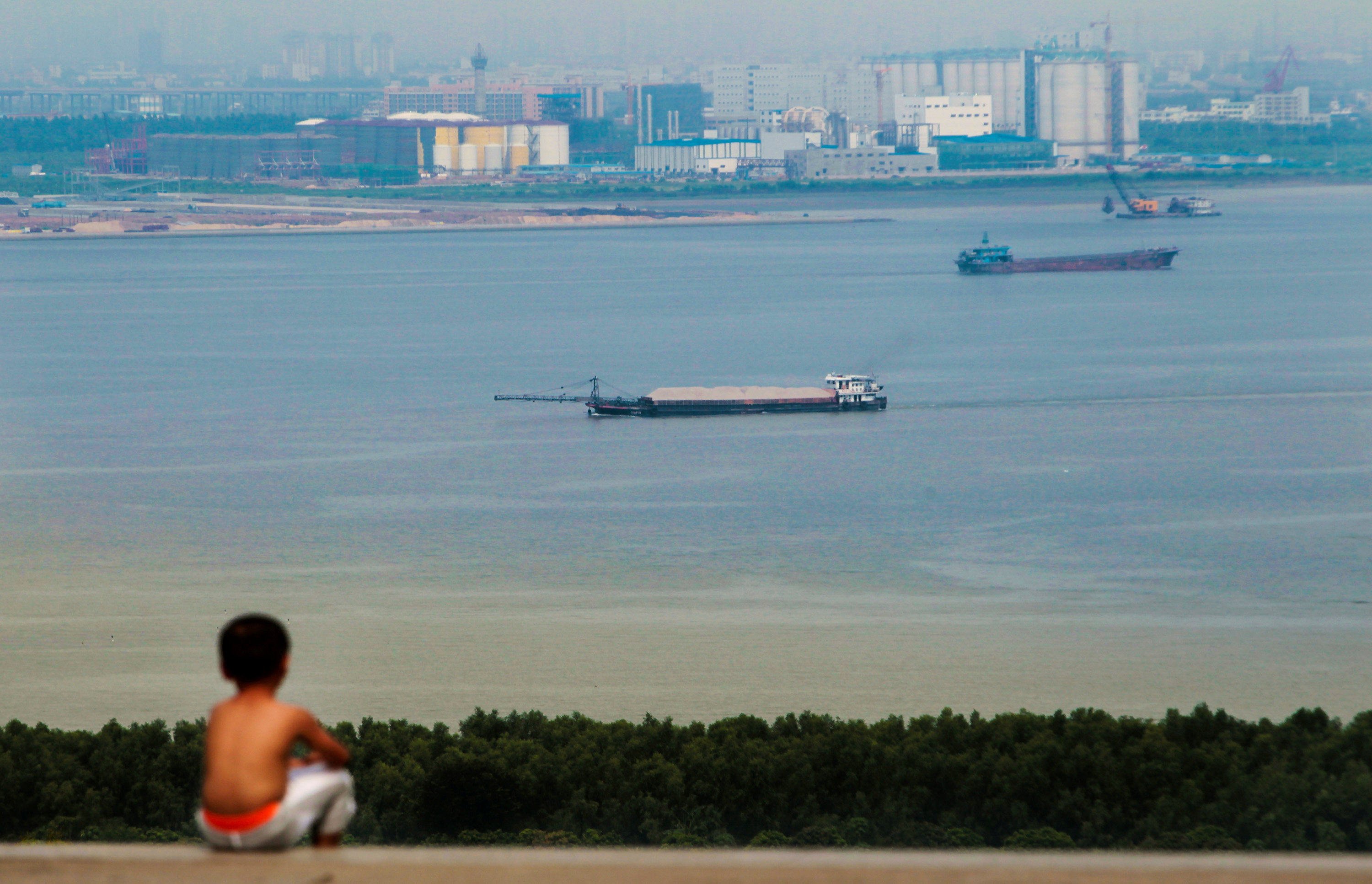 A boy looks at cargo ships passing along the Pearl River in Guangzhou in China’s Guangdong province in August  2014. Chinese shipping giant Cosco recently launched its first fully electric vessel. Photo: Reuters