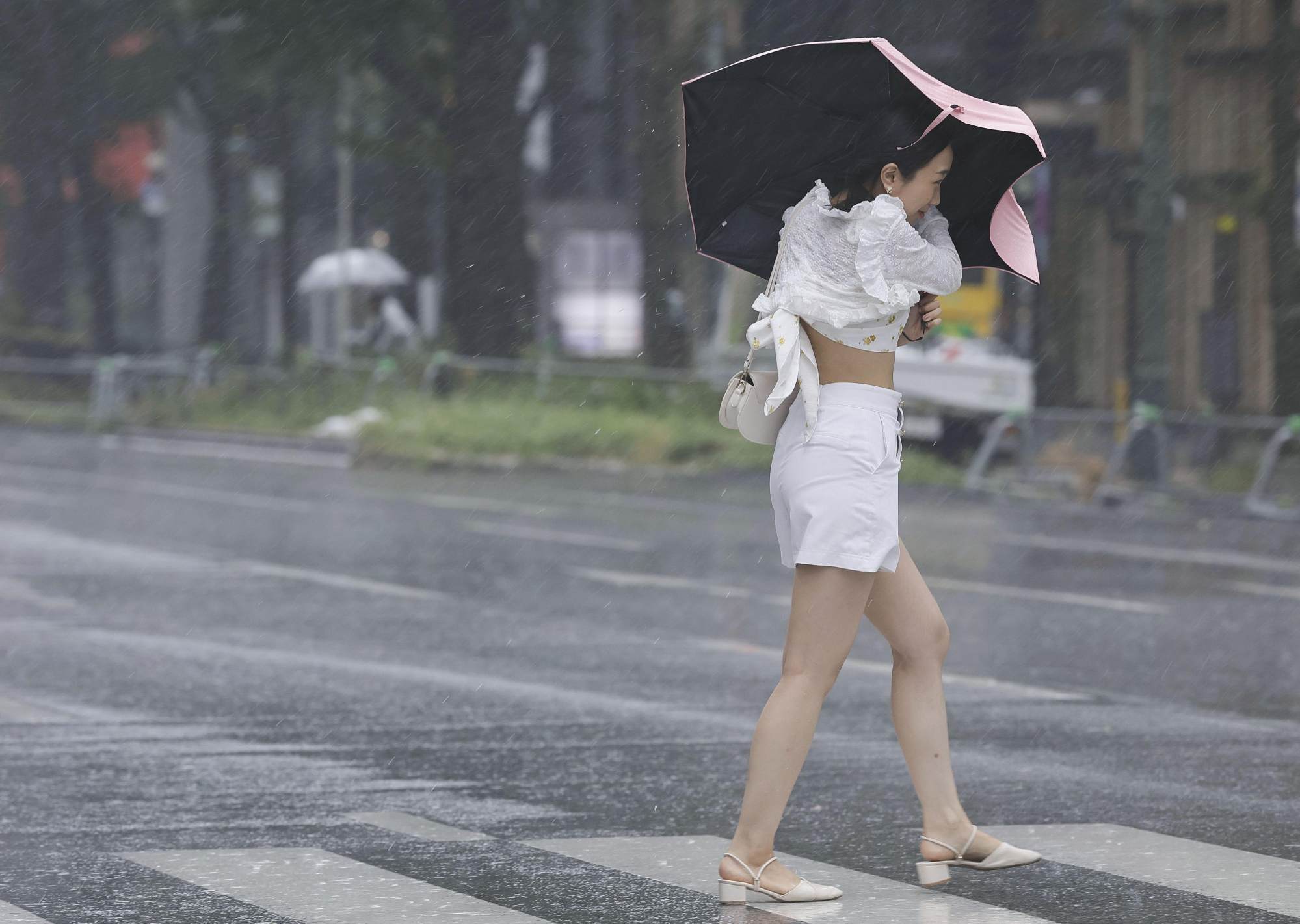 A woman braves a downpour and strong wind in Osaka on Tuesday as Typhoon Lan hits the region. Photo: Kyodo