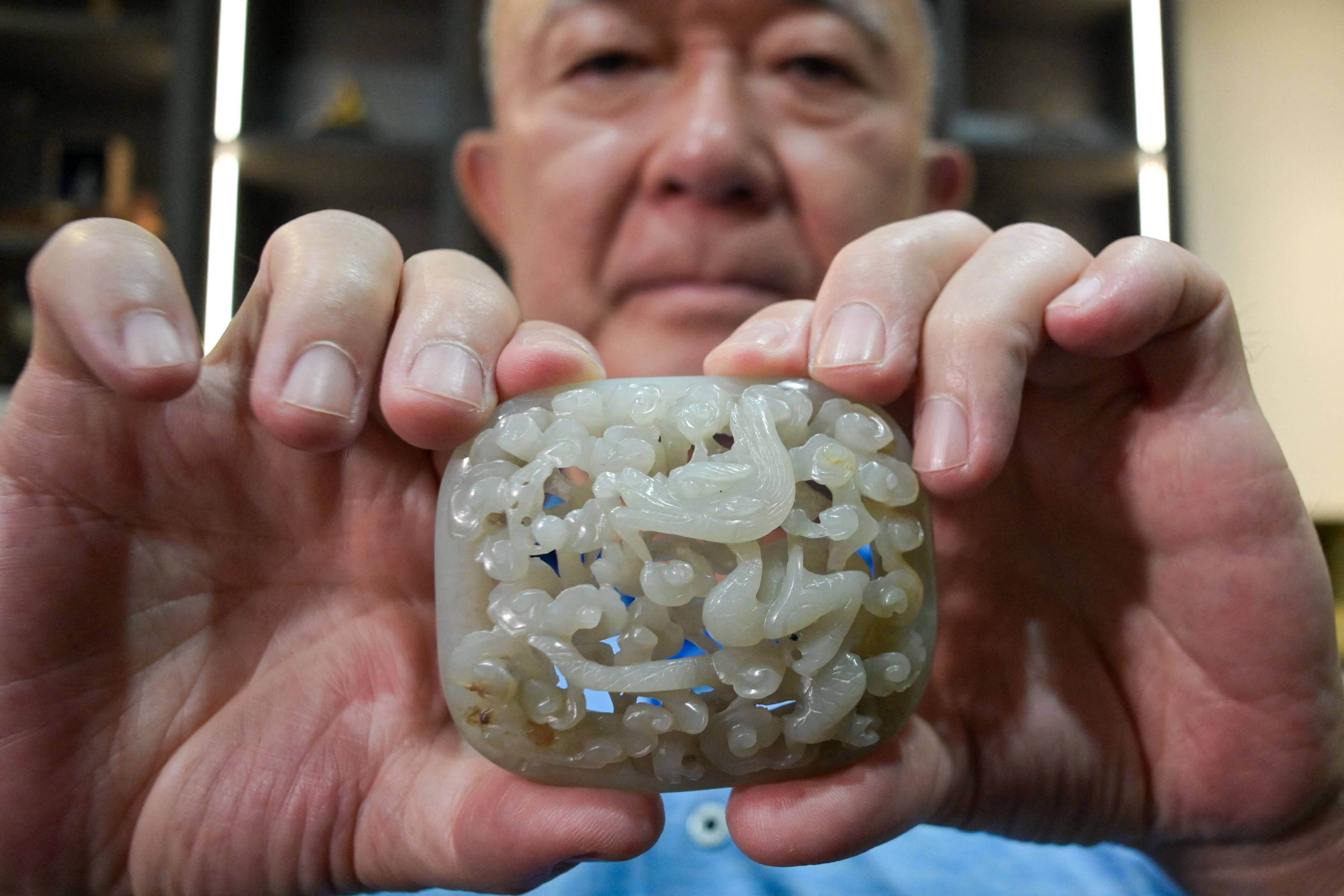 Chang Juben, chairman of Taiwan’s Association of Jade Collectors, holds a Yuan dynasty jade belt ornament showing a carving of a dragon among clouds, in Taipei, on July 19, 2023. Taiwan’s antique jade market is flagging post-Covid, partly due to Taipei’s worsening ties with Beijing. Photo: AFP