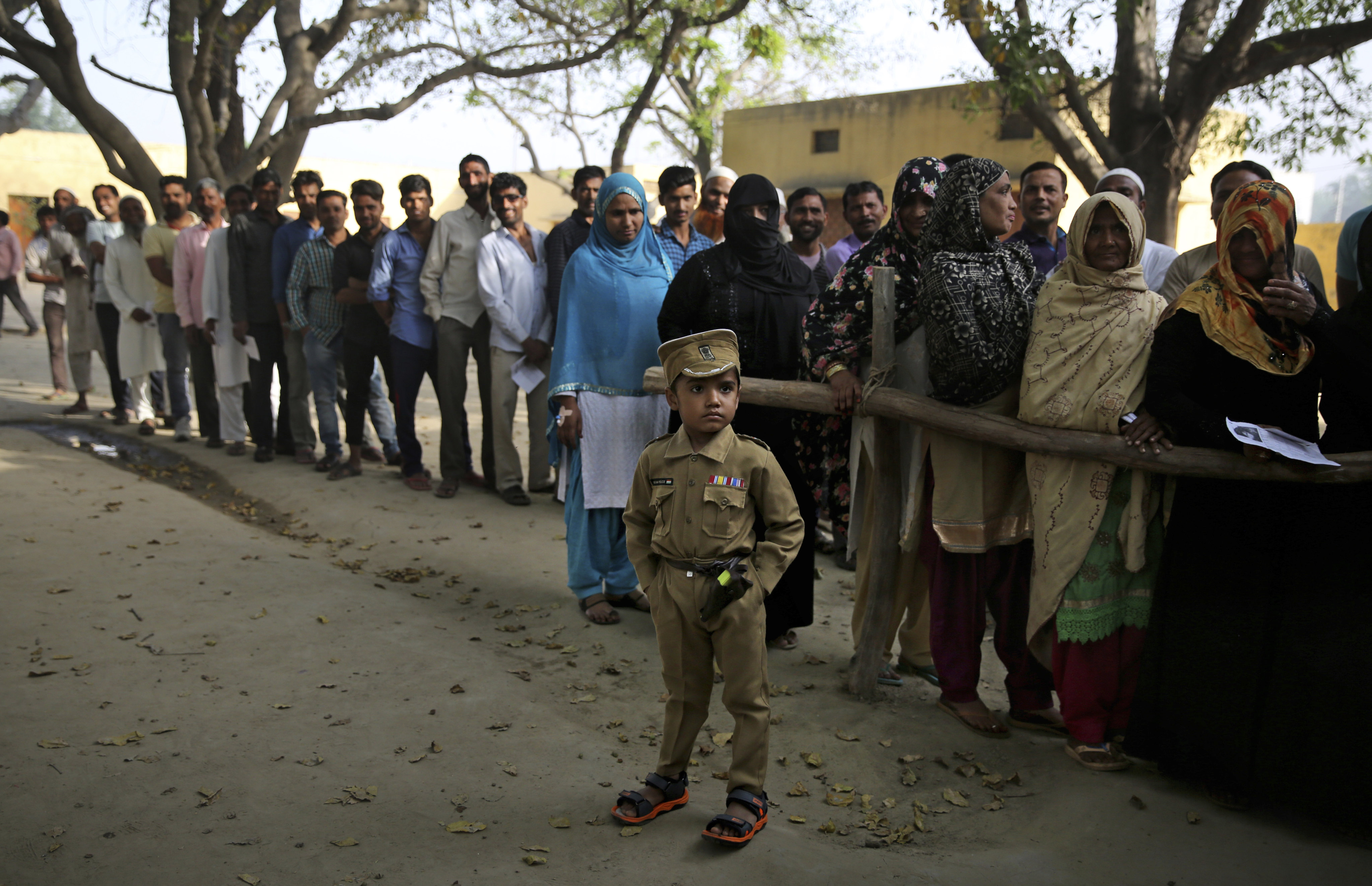 A boy dressed as a policeman stands as people queue to cast their votes in a village near Meerut, Uttar Pradesh, India, in 2019. Photo: AP 