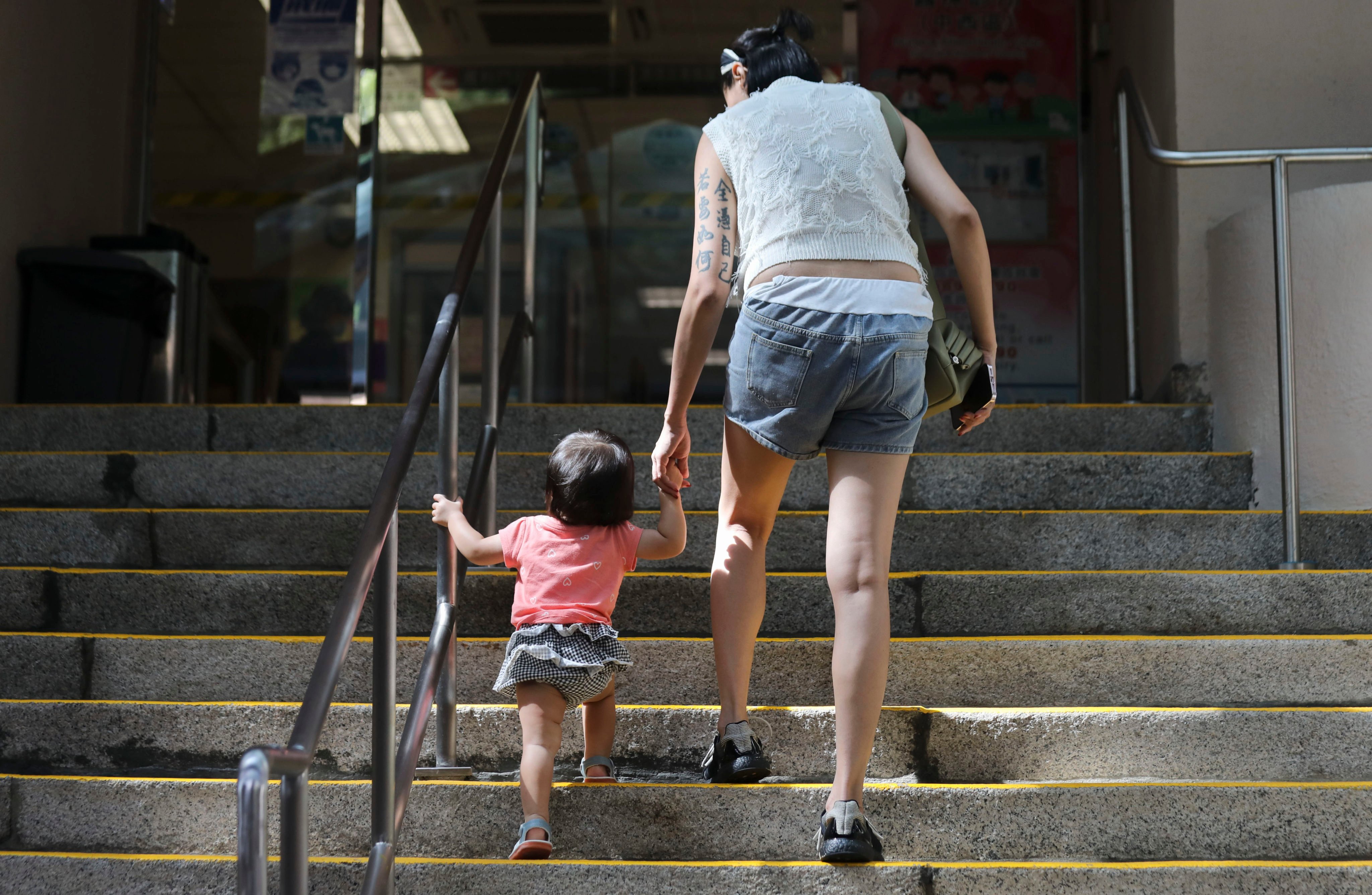 A woman with a toddler enters Tsan Yuk Hospital in Sai Ying Pun on August 15. Hong Kong’s fertility rate has hit a record low, sparking calls for reforms to provide more support to young families and make the city more family-friendly. Photo: Xiaomei Chen