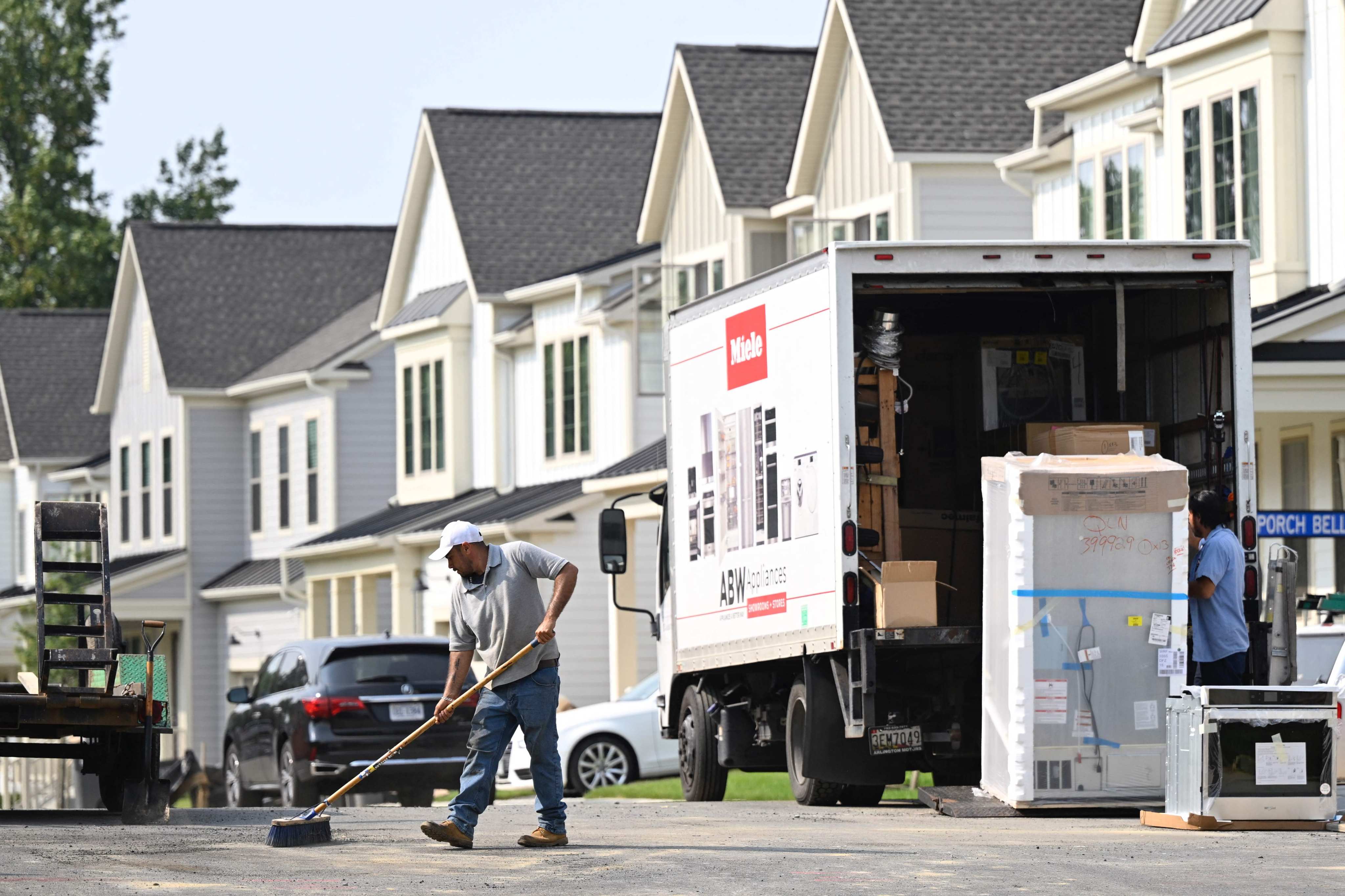 A maintenance worker sweeps the street in front of a row of new homes in Fairfax, Virginia, on August 22. Sales of homes in the United States fell in July as elevated mortgage rates and limited housing supply held buyers back. Photo: AFP