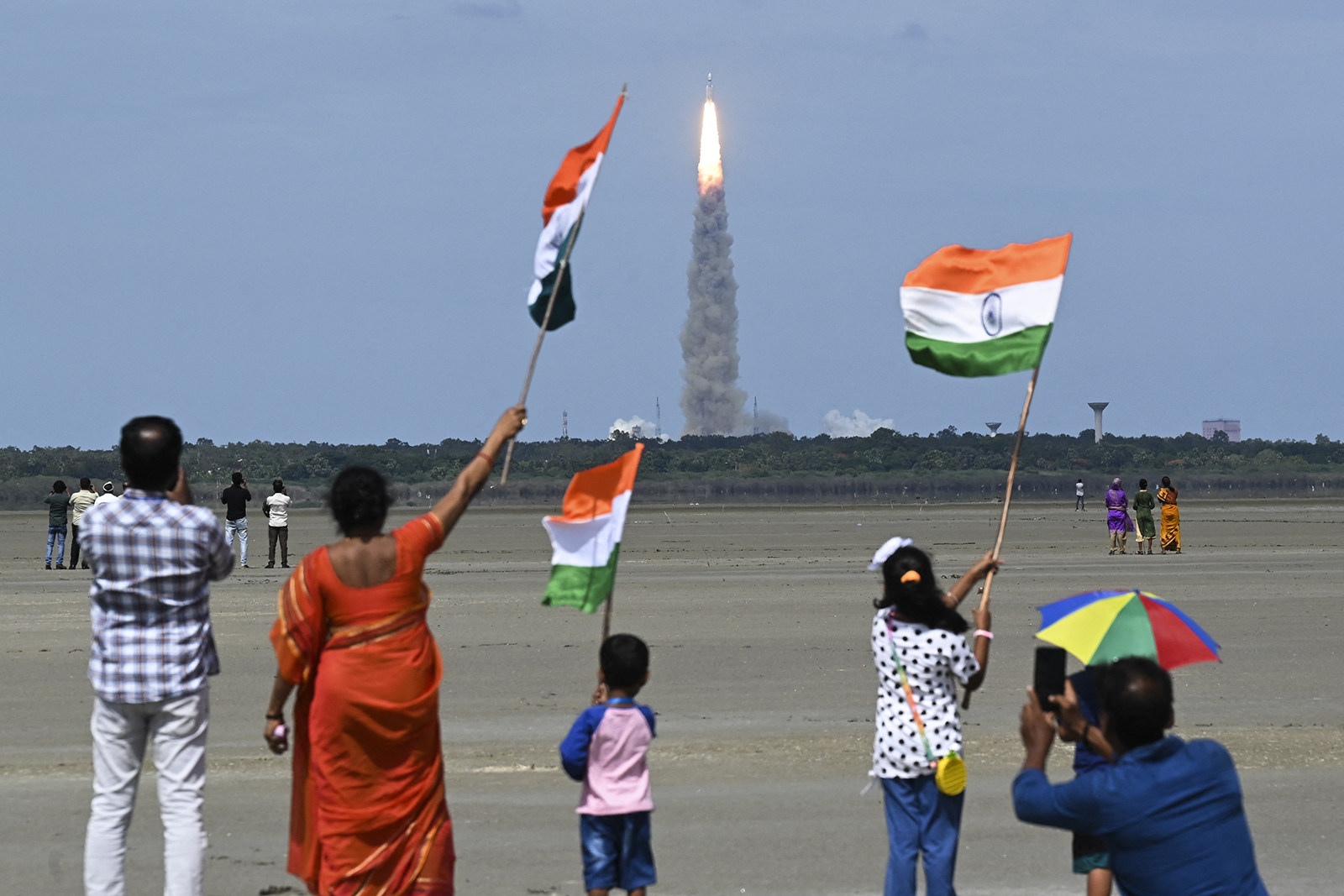 People wave Indian flags as a rocket carrying the Chandrayaan-3 spacecraft lifts off from India on July 14. India joined the United States, the Soviet Union and China as only the fourth country to successfully land on the moon. Photo: AFP