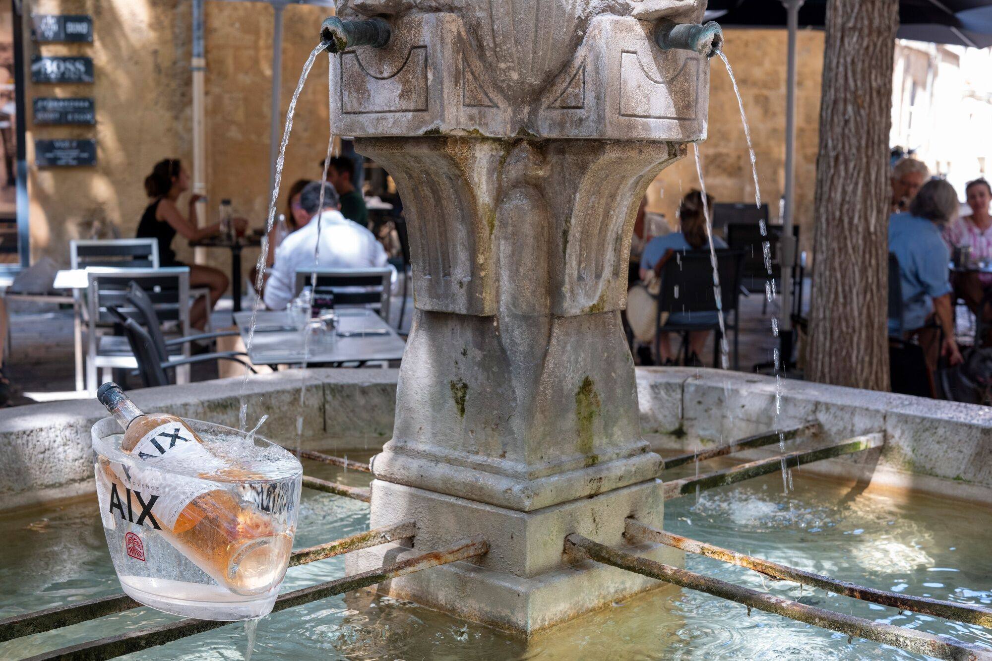 A bottle of Aix Rose wine cools in the waters of a street fountain in Aix-en-provence, France. Photo: Bloomberg