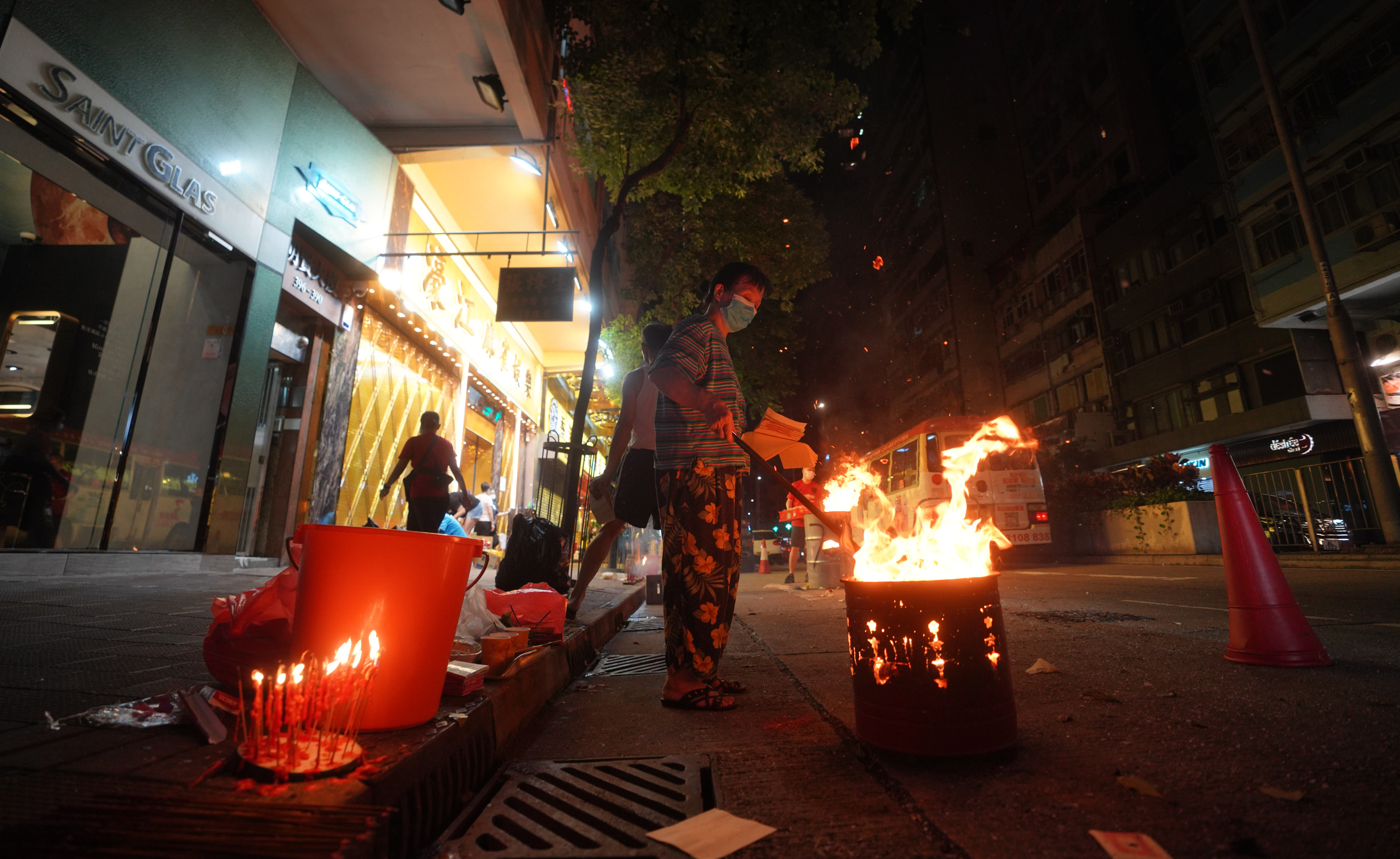 It is common in Chinese communities to see people, such as these men in Wan Chai, Hong Kong, burning paper offerings in the street during the Hungry Ghost Festival – to help wandering ghosts when they return to the afterlife. Photo: Winson Wong